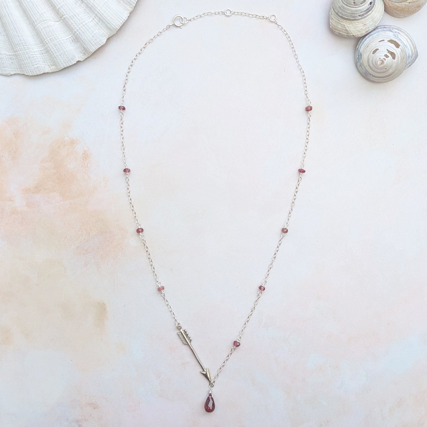 Necklace with a Pink Tourmaline teardrop pendant on a light background with shells