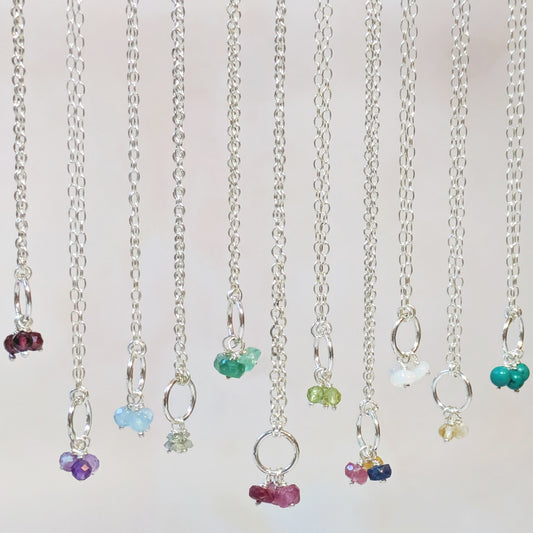 Collection of silver necklaces with colourful ethically sourced gemstone beads on a light background