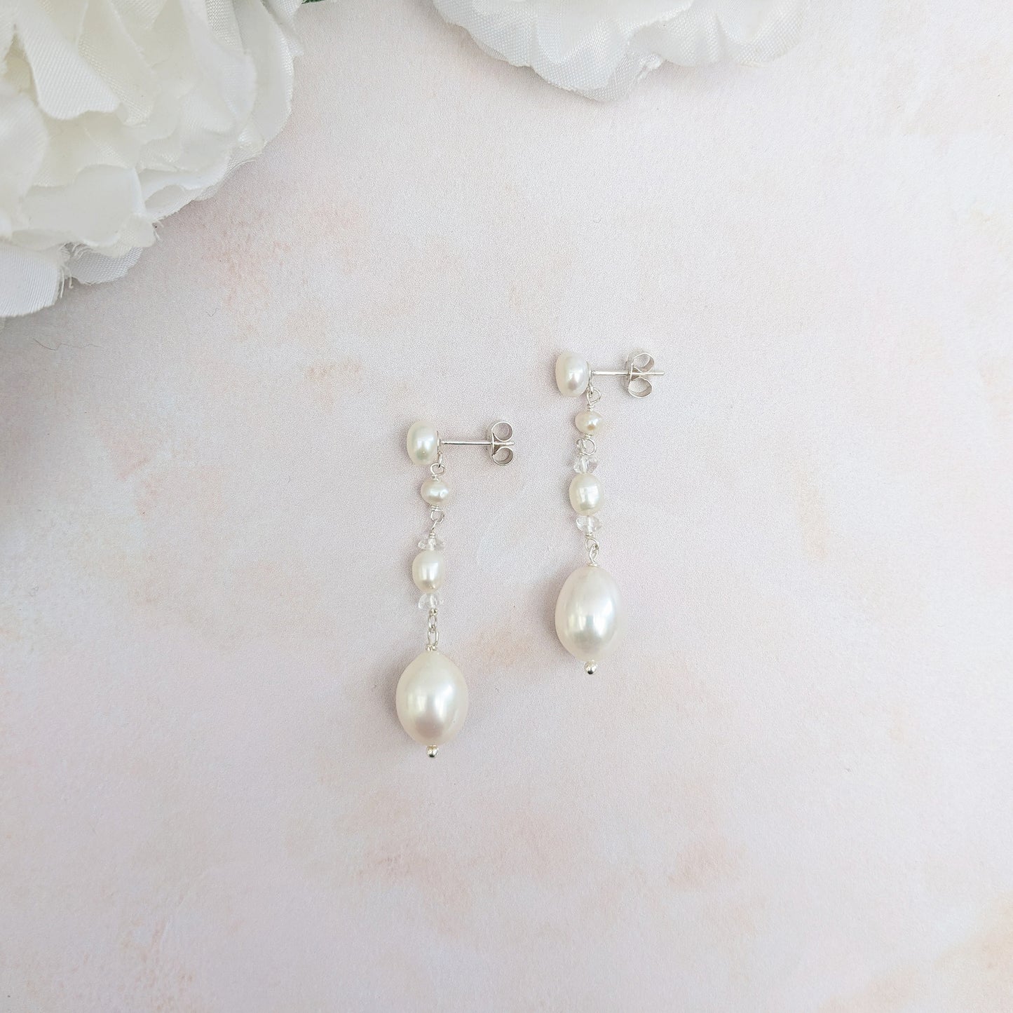 Pearl & white topaz dangle earrings for brides pictured on a neutral background designed & handmade by Susie Warner.