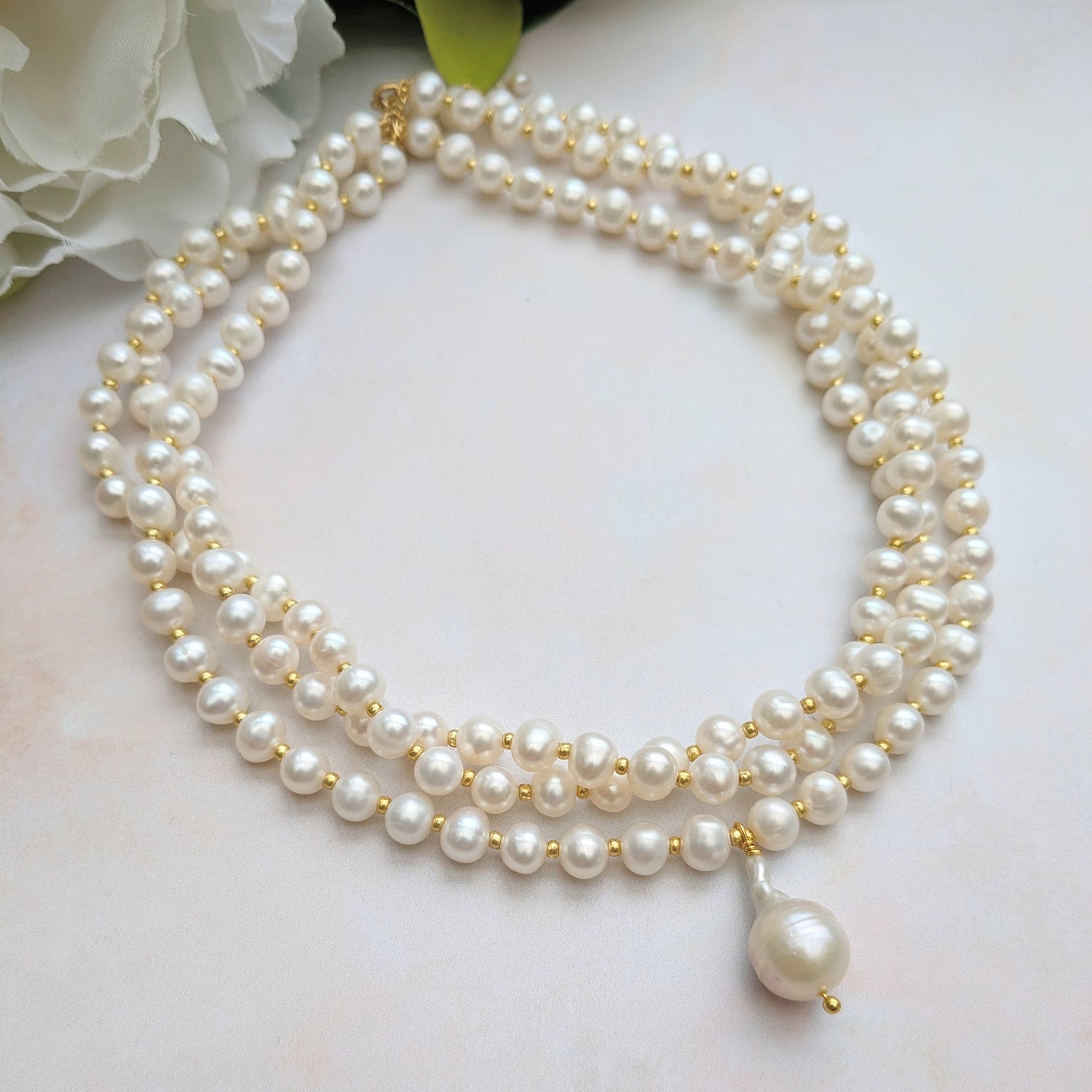 Pearl bridal necklace on a white background with flowers.