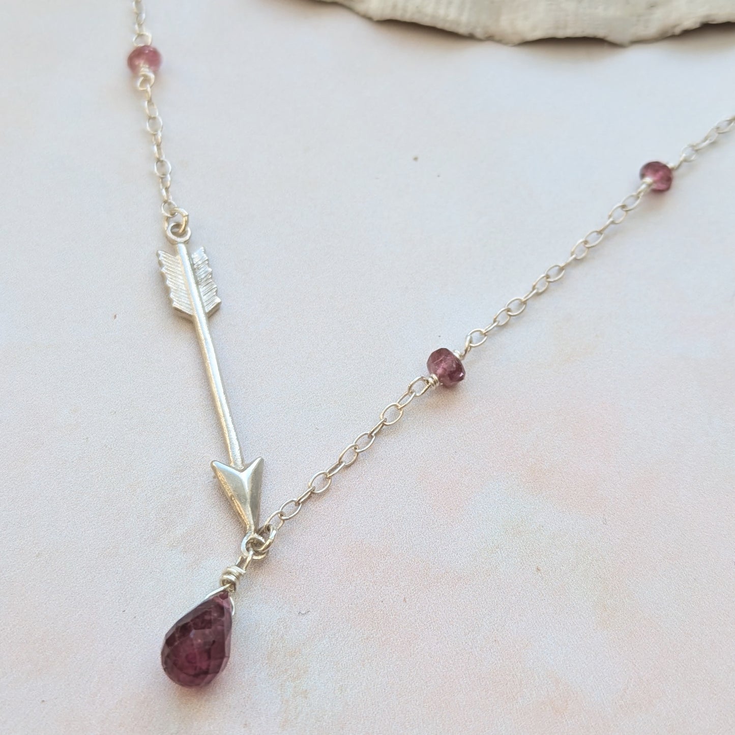 Necklace with silver arrow pendants and Pink Tourmaline semi precious gemstone beads on a light background