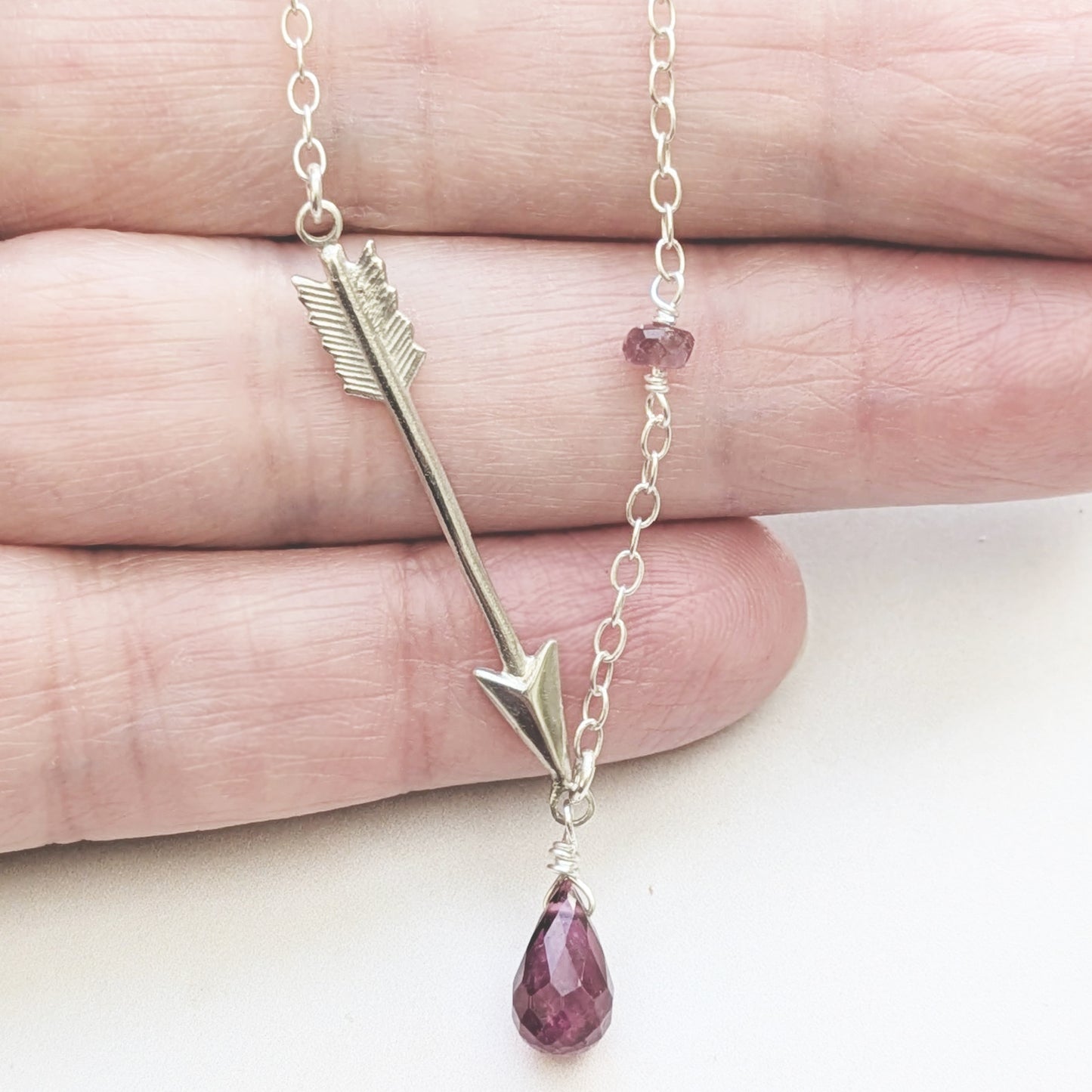 Necklace with arrow and Pink Tourmaline teardrop pendant on a hand