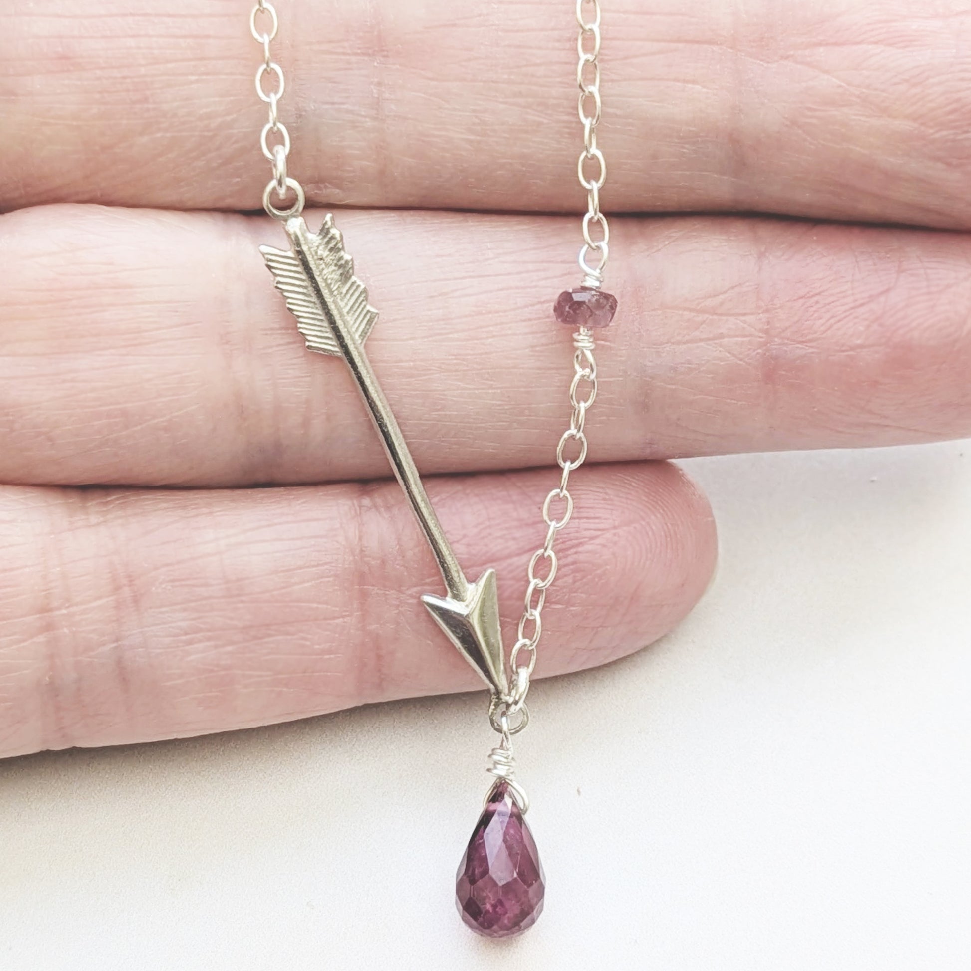Necklace with arrow and Pink Tourmaline teardrop pendant on a hand