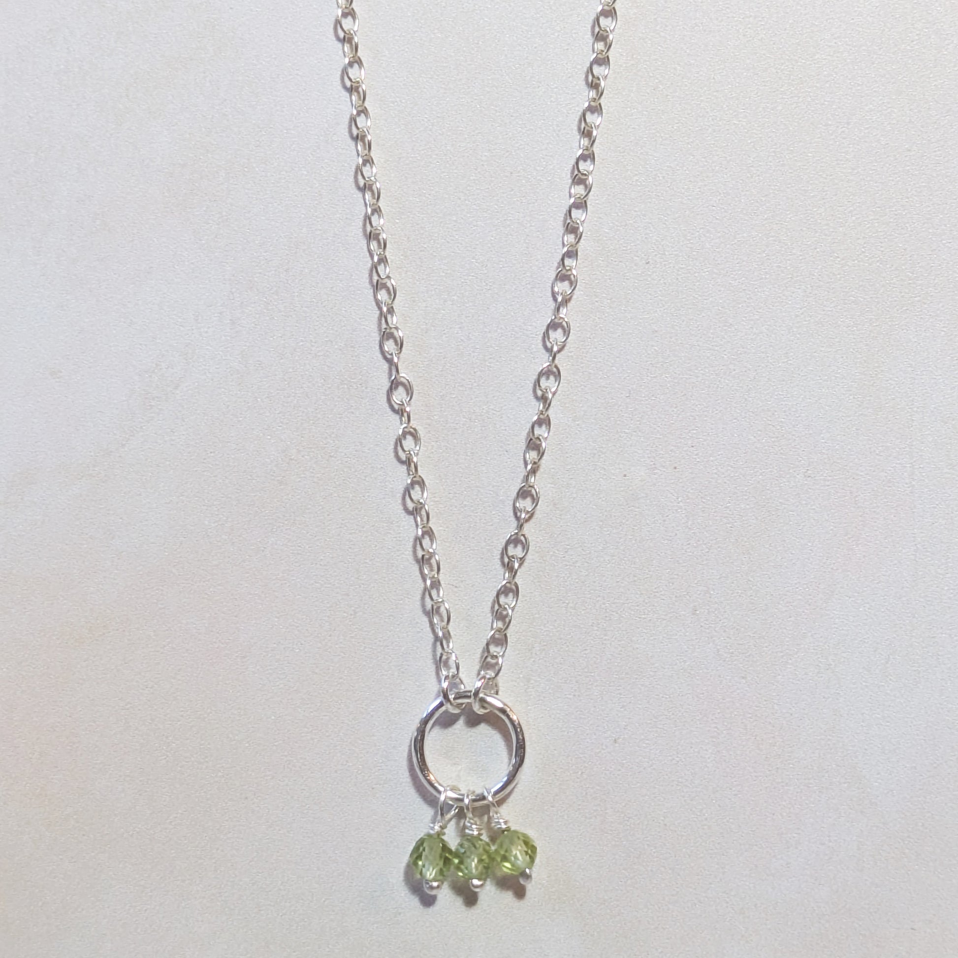 Silver necklace with Peridot gemstones on a white background.
