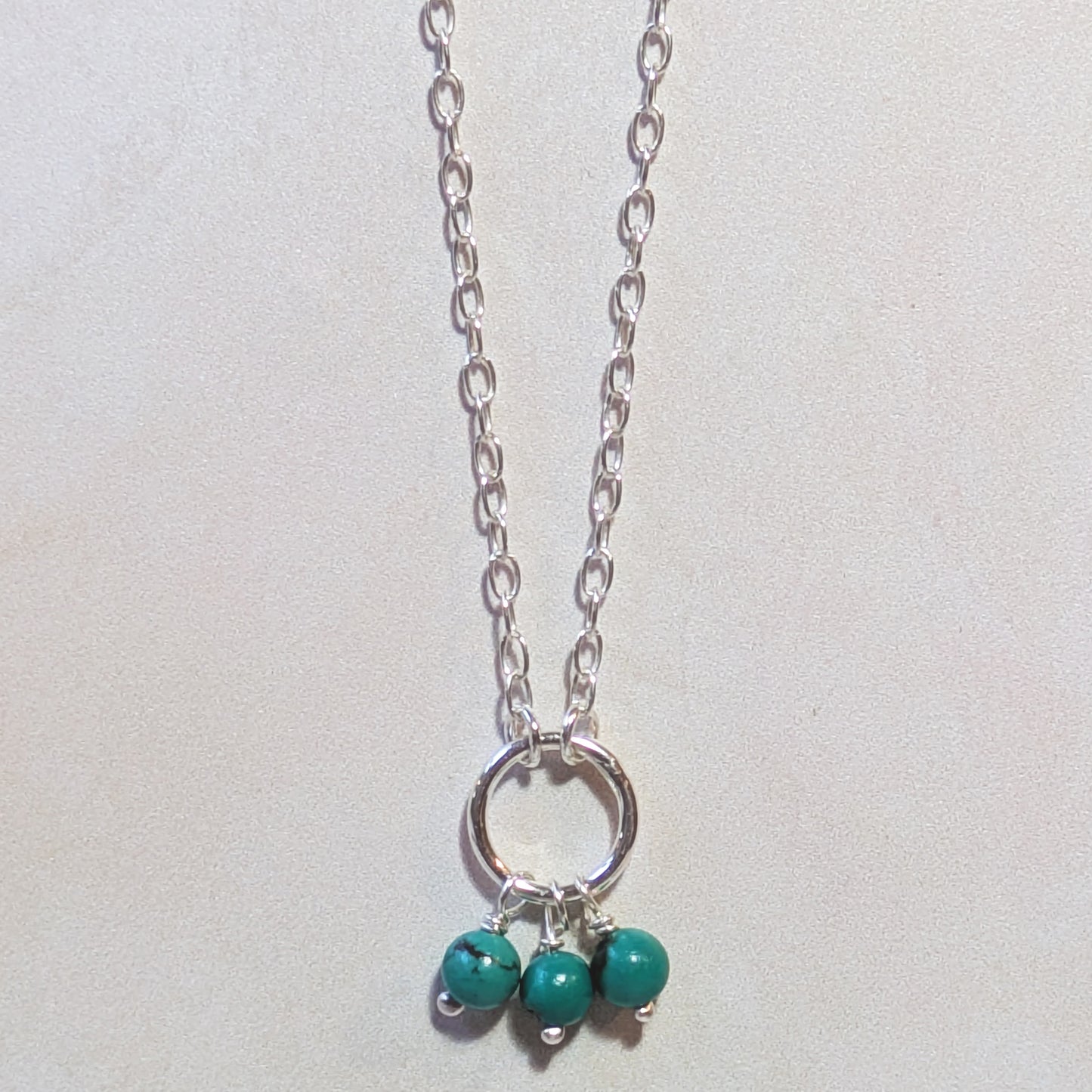 Necklace with natural Arizona Turquoise beads and a silver circle pendant on a light background.