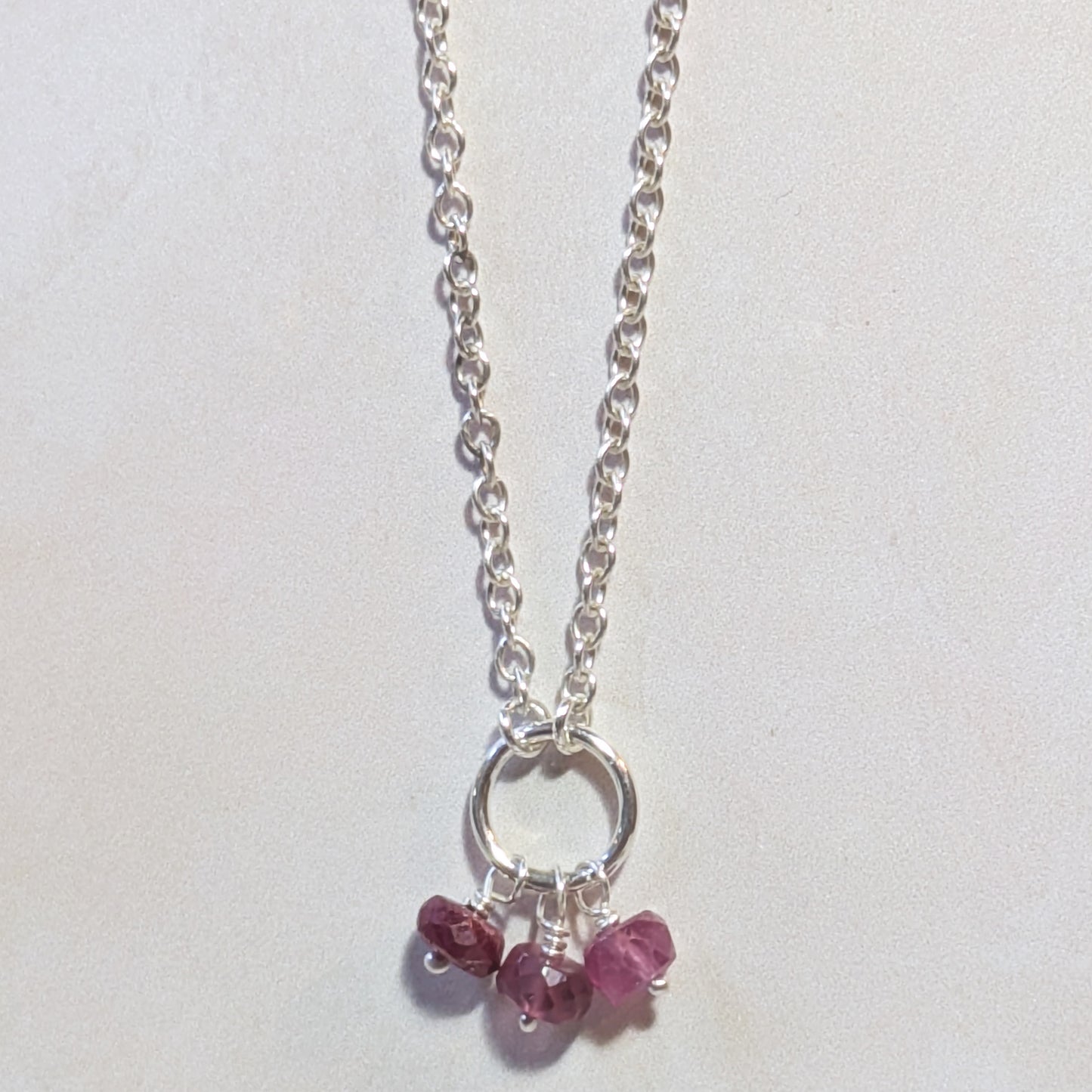 Silver necklace with small Ruby gemstone beads on a white background.