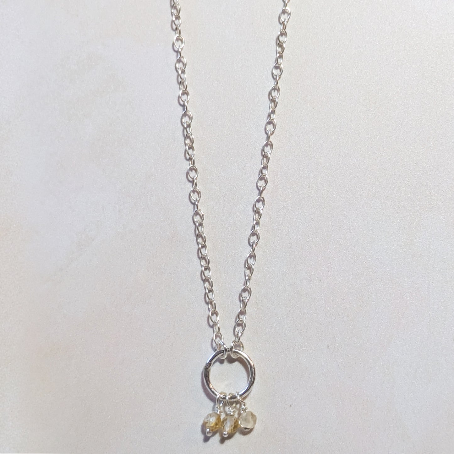 Silver necklace with a small Citrine pendant on a white background.