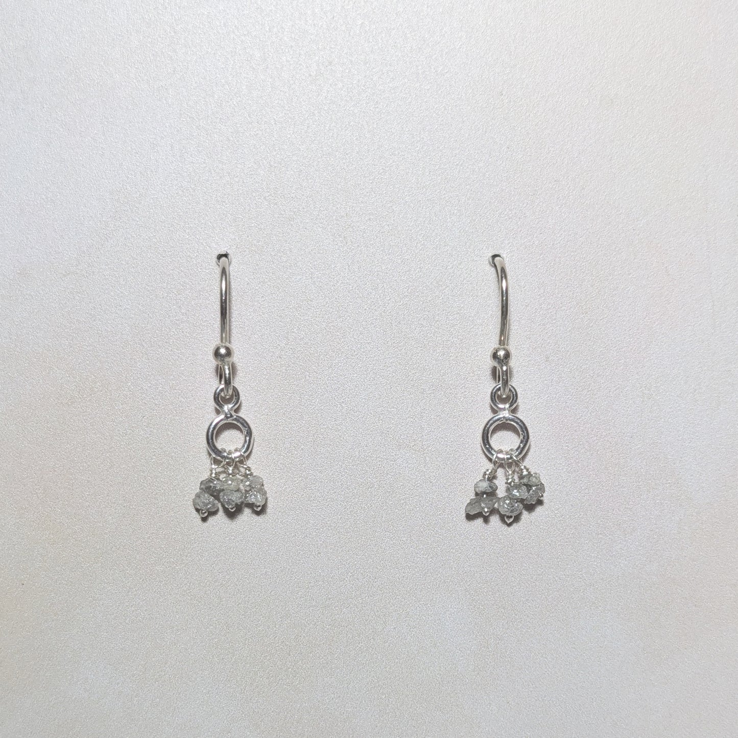 silver dangling drop earrings with rough diamond nugget charms on a white background.