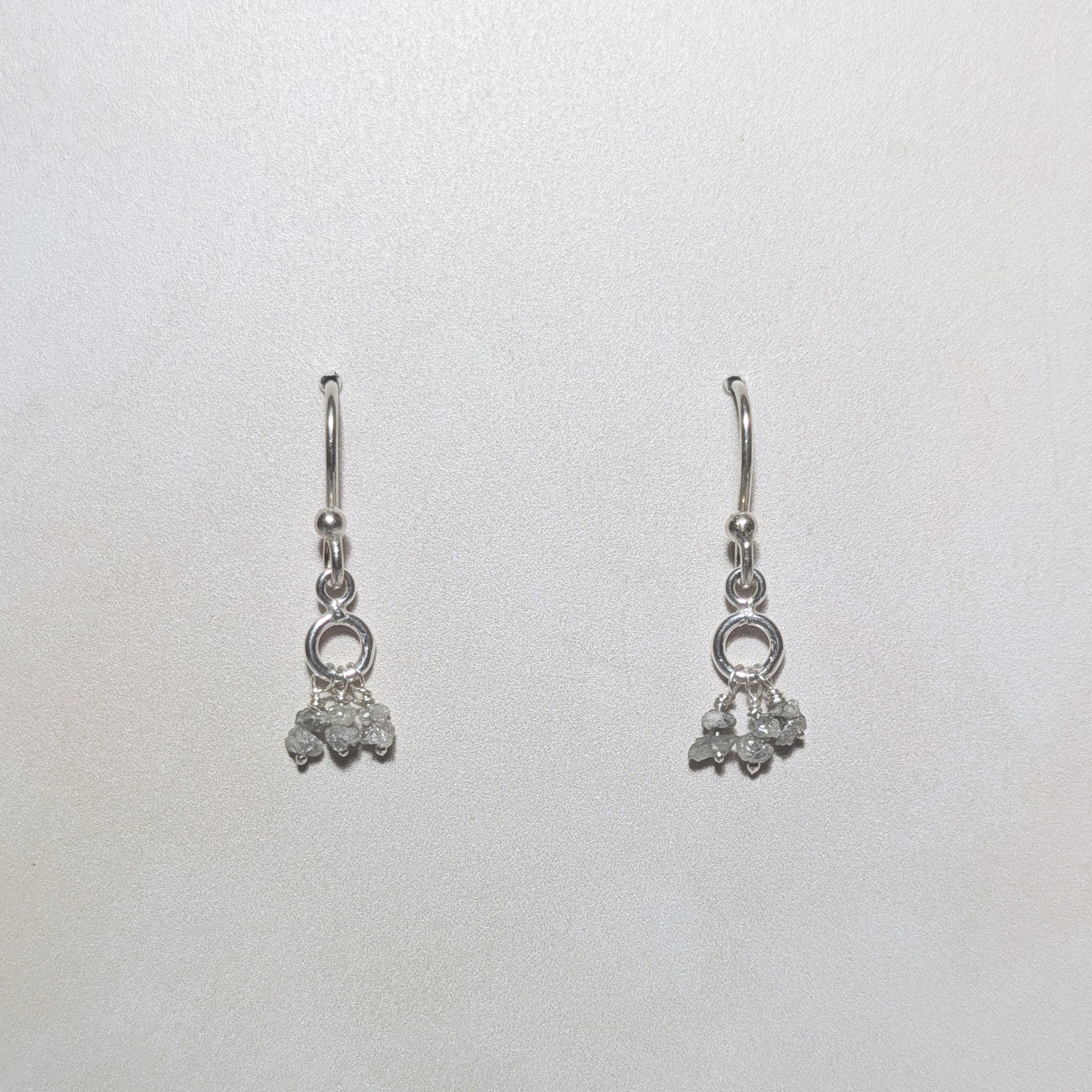 silver dangling drop earrings with rough diamond nugget charms on a white background.