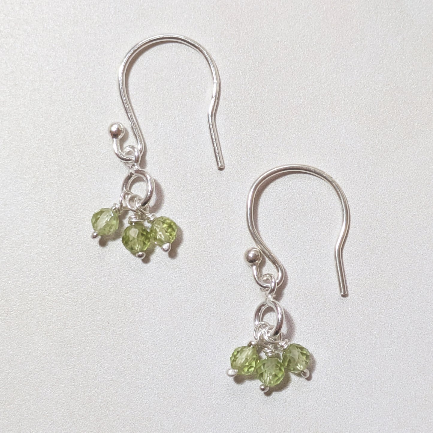 Silver hookwire earrings with Peridot gemstone drops on a white background.