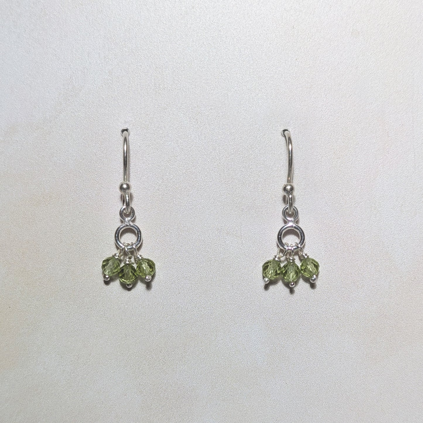 silver drop earrings with Peridot gemstone charms on a white background.