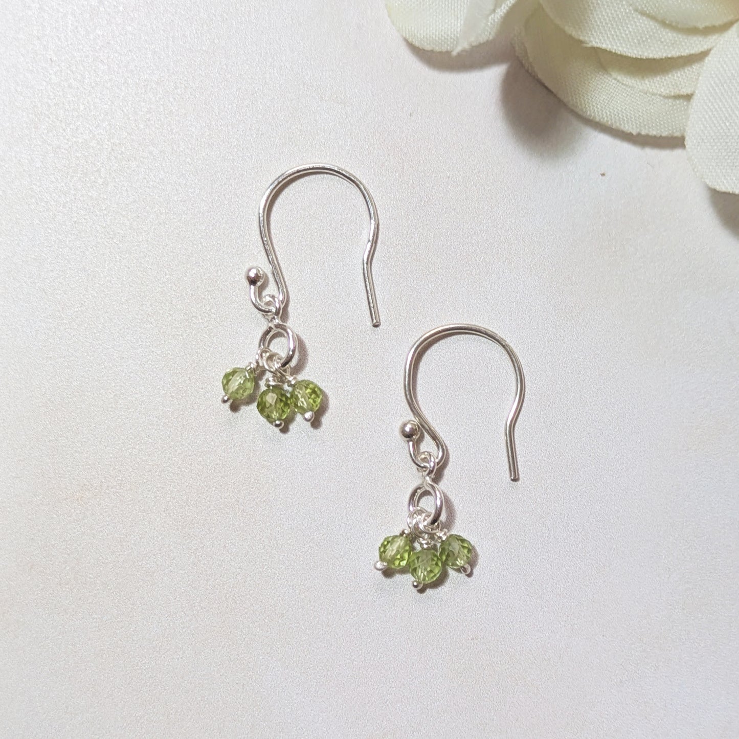 Silver earrings with August birthstone gemstones on a white background.