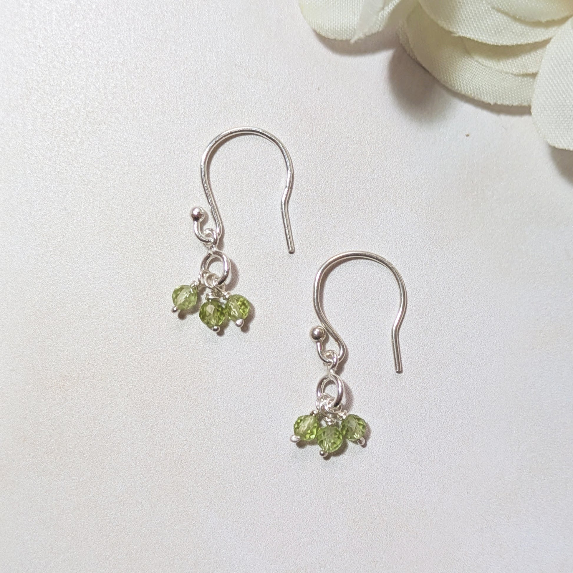 Silver earrings with August birthstone gemstones on a white background.