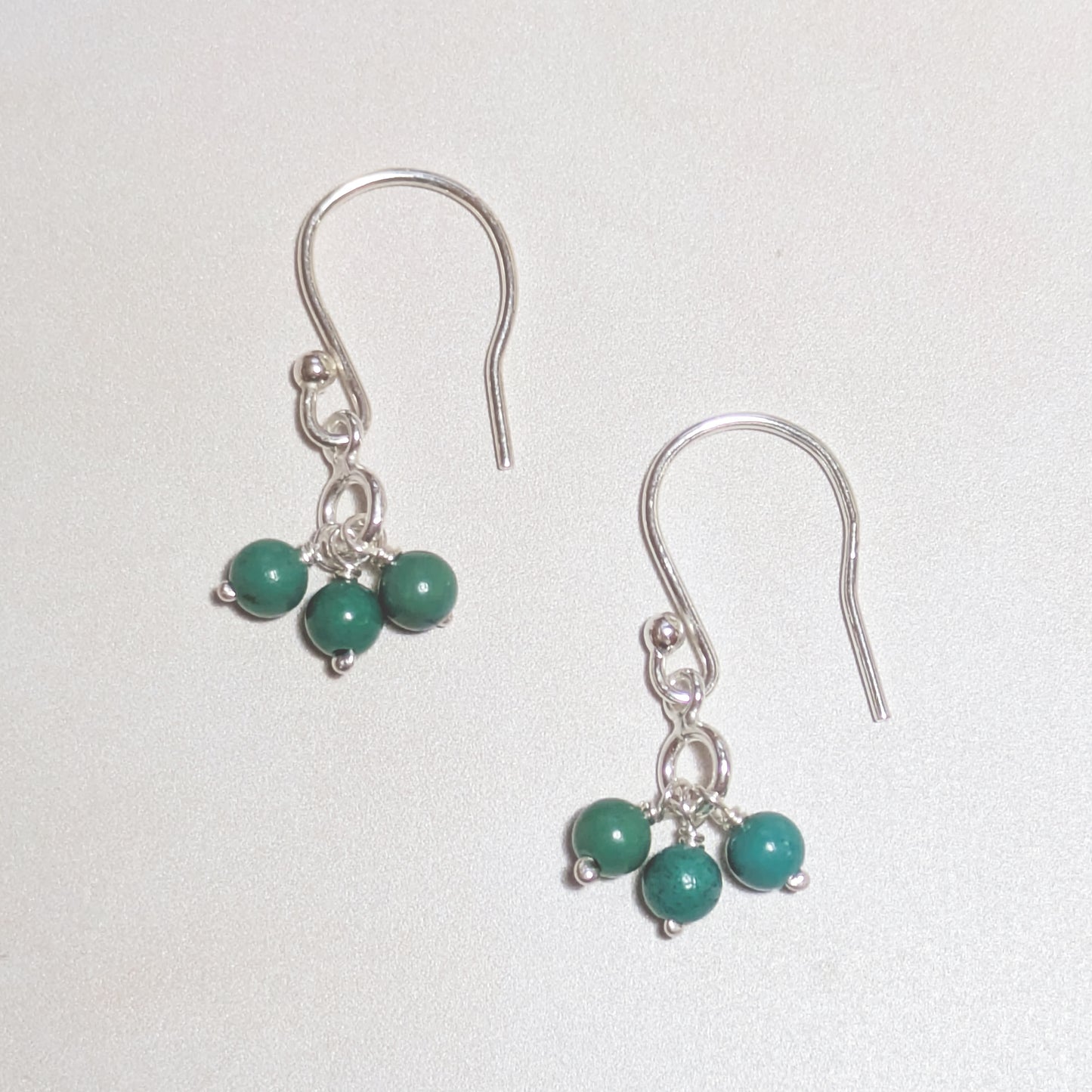 silver drop earrings with natural Turquoise gemstone beads on a white background.