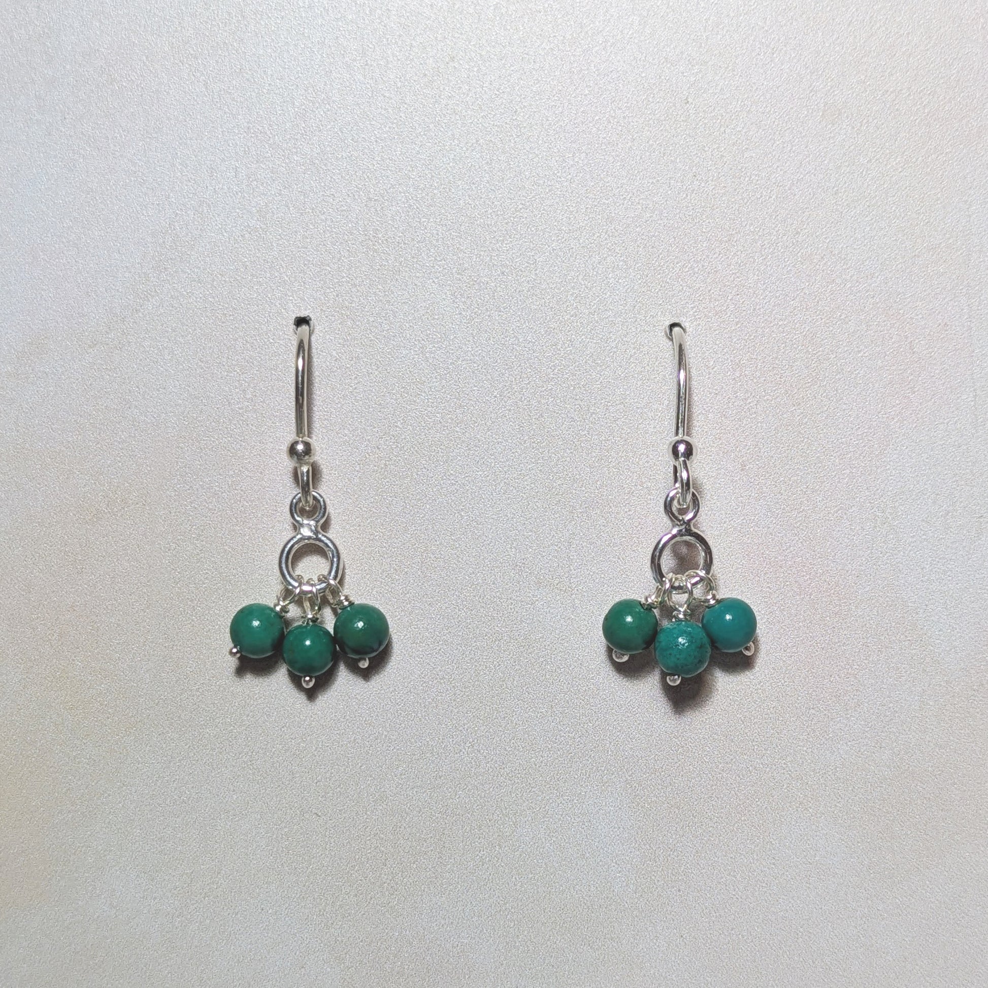 Pair of earrings with natural Arizona Turquoise charm drops on a white background.