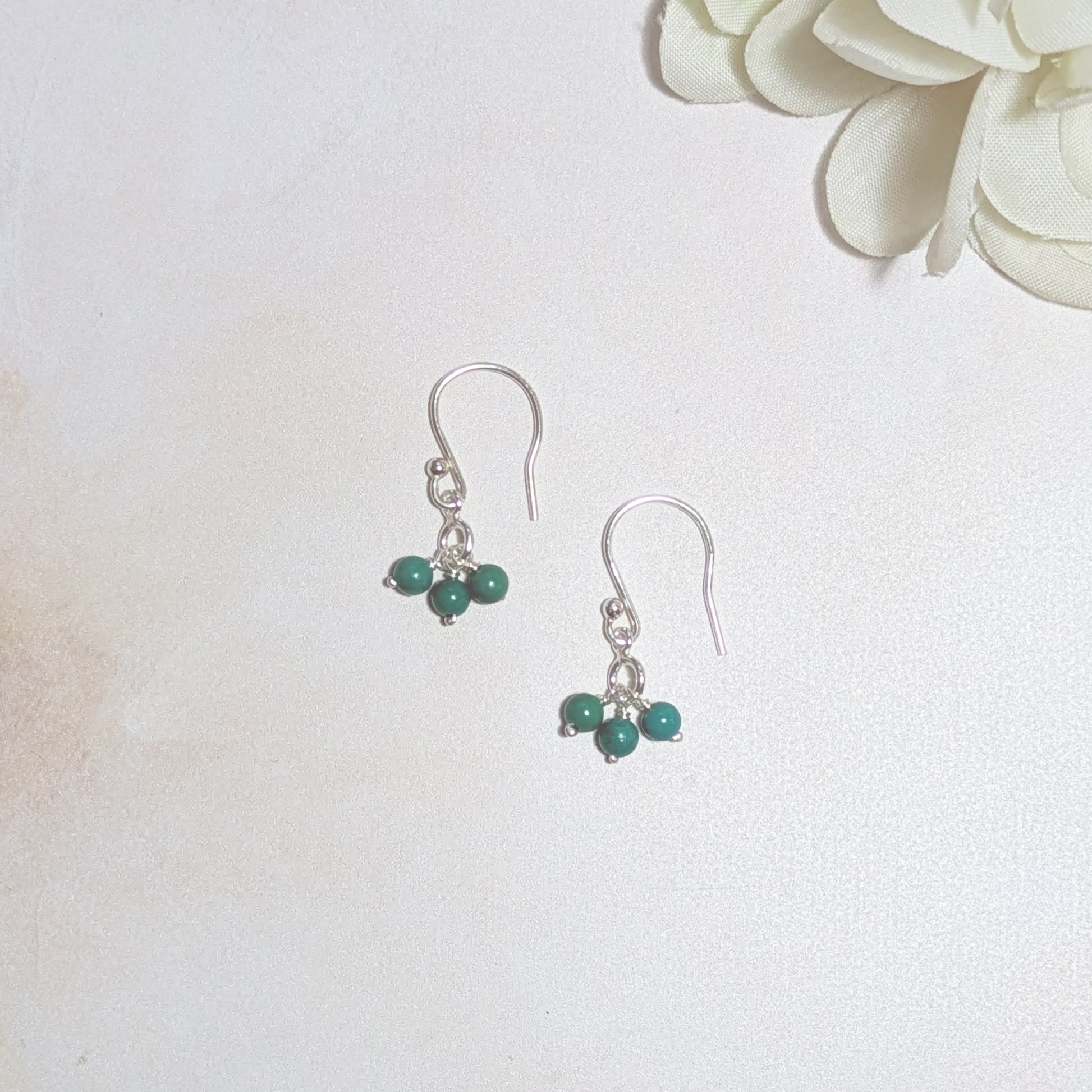 Silver earrings with natural Turquoise beads on a white background.