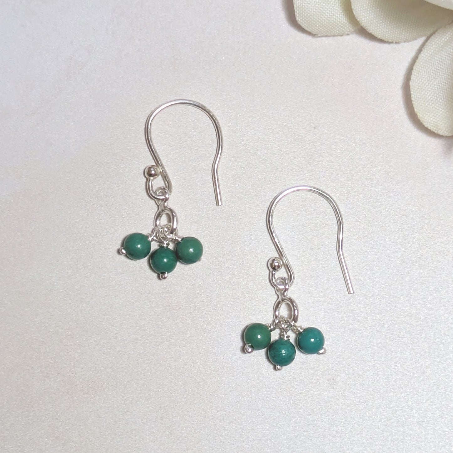 Silver earrings with natural Arizona Turquoise beads on a white background.