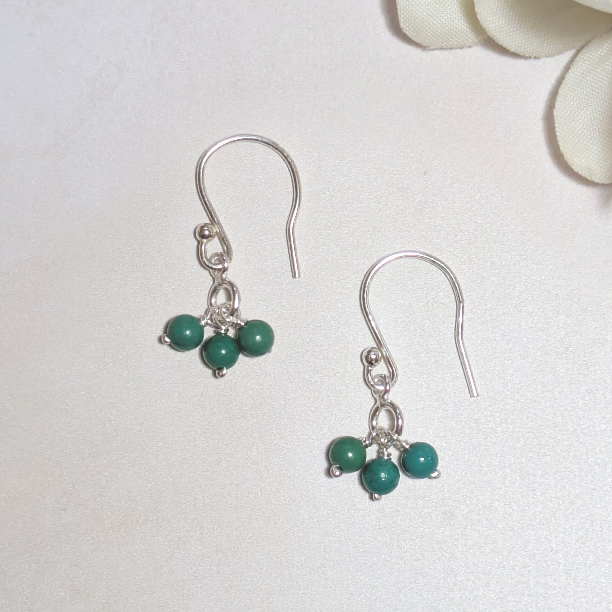 Silver earrings with natural Arizona Turquoise beads on a white background.