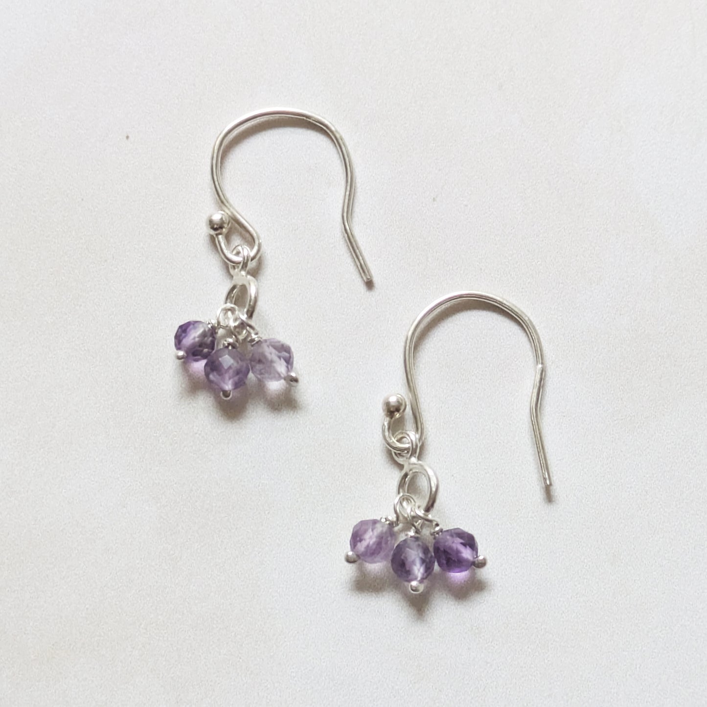 silver dangling earrings with Amethyst gemstone charms on a white background.