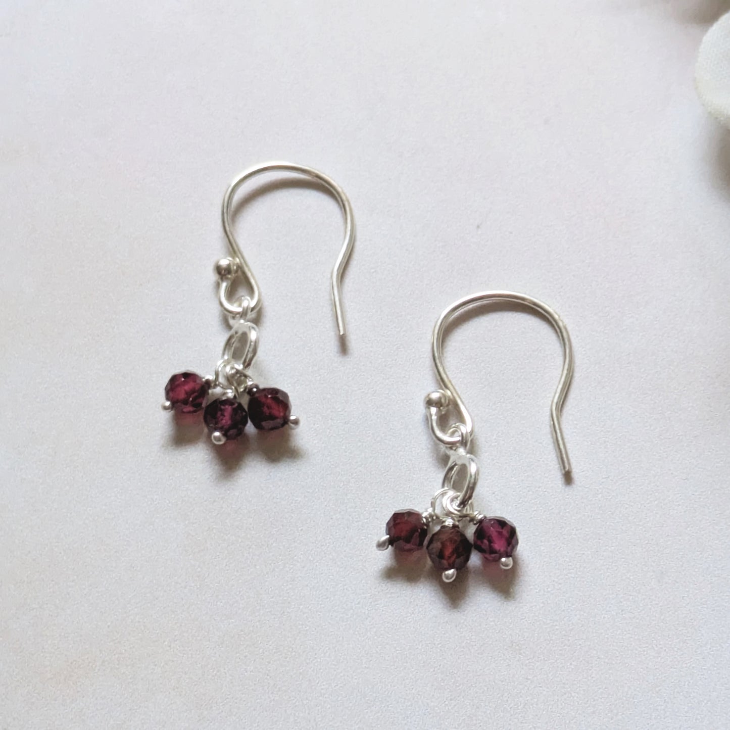 silver charm drop earrings with Garnet gemstone beads on a white background.
