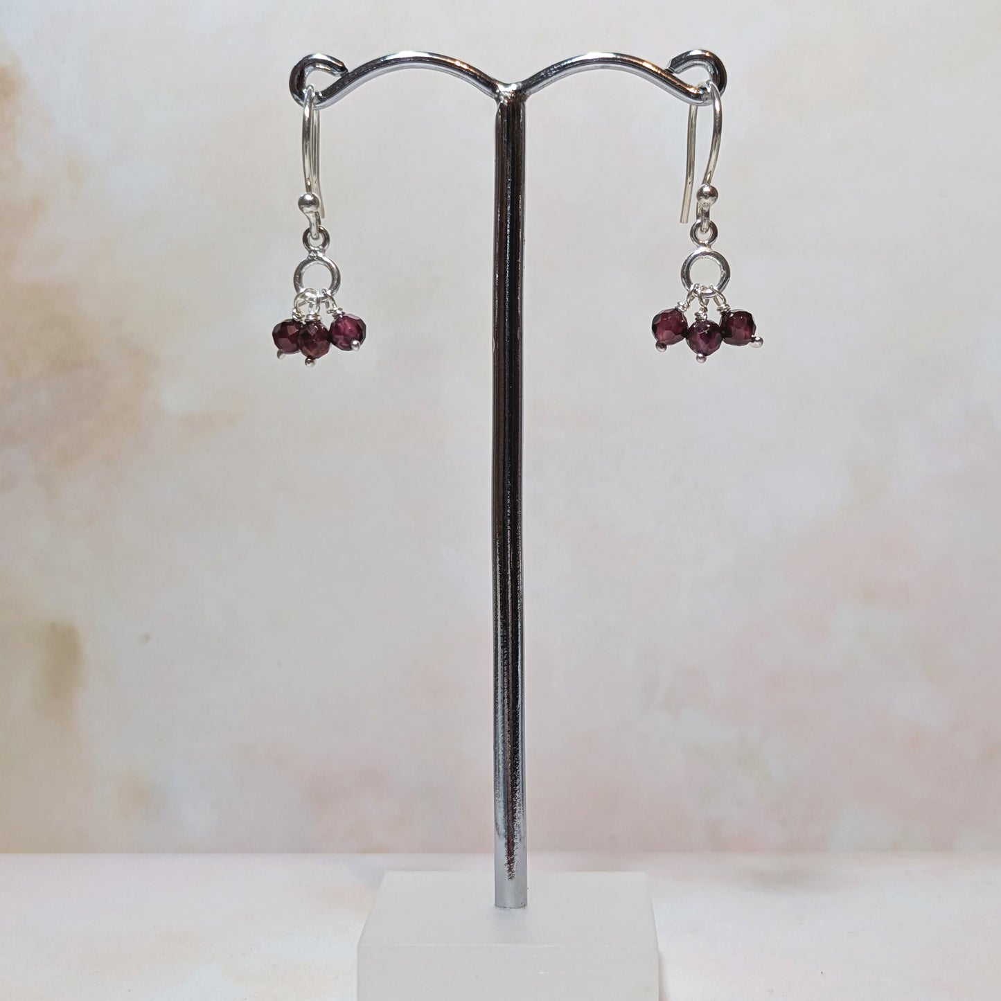 silver drop earrings with January birthstone gemstones against a neutral background.