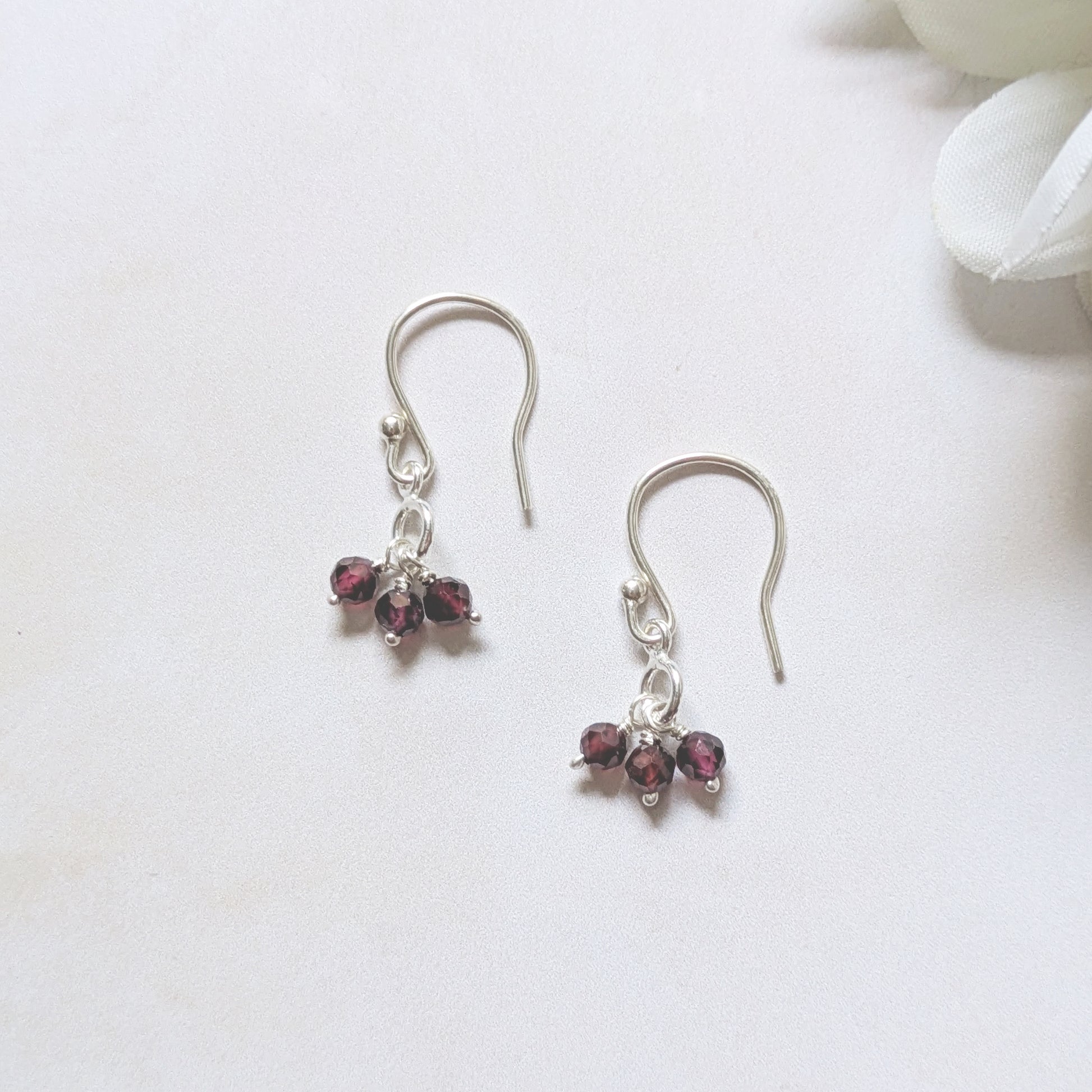 silver hookwire drop earrings with Garnet gemstone charm drops on a white background.