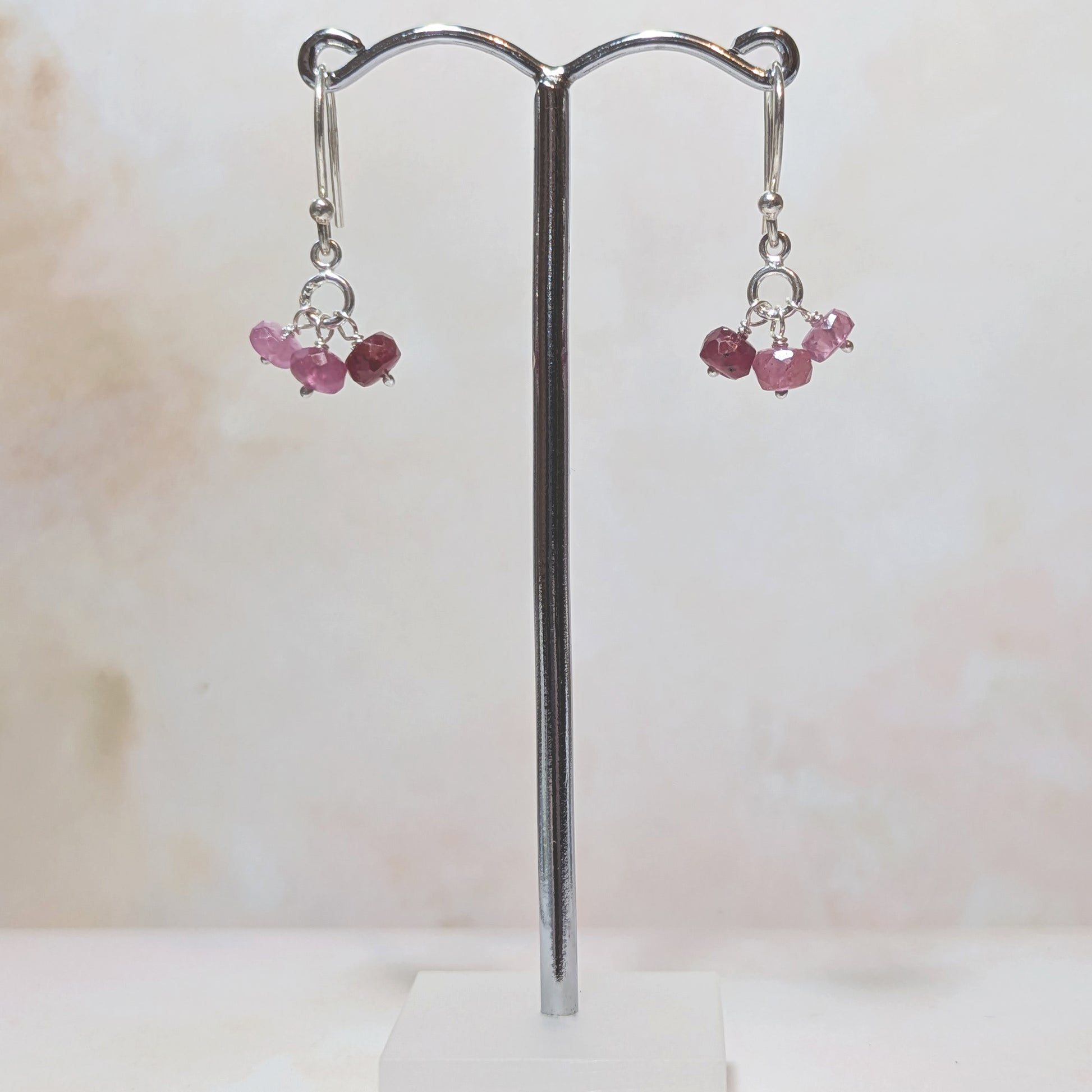Pair of earrings with Rubies on a stand against a white background.