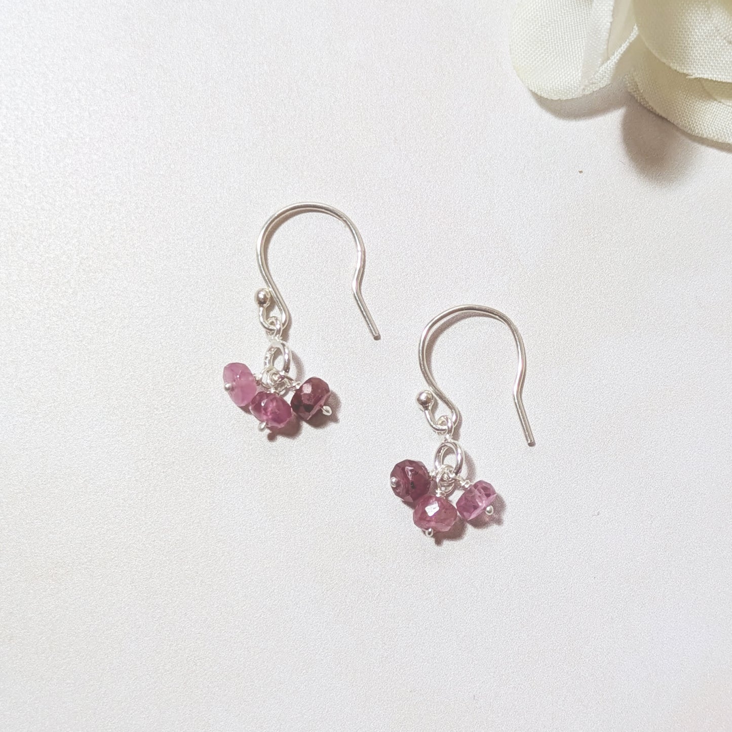 Silver earrings with Ruby gemstones on a white background.