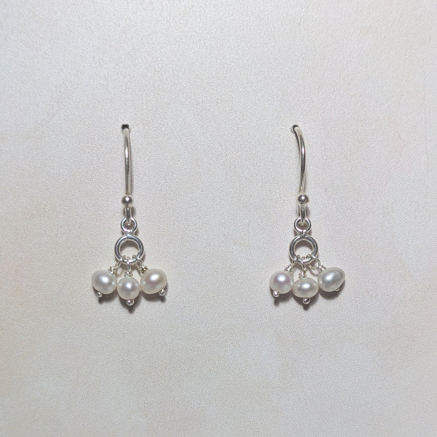 silver dangly drop earrings with freshwater pearl beads on a white background.
