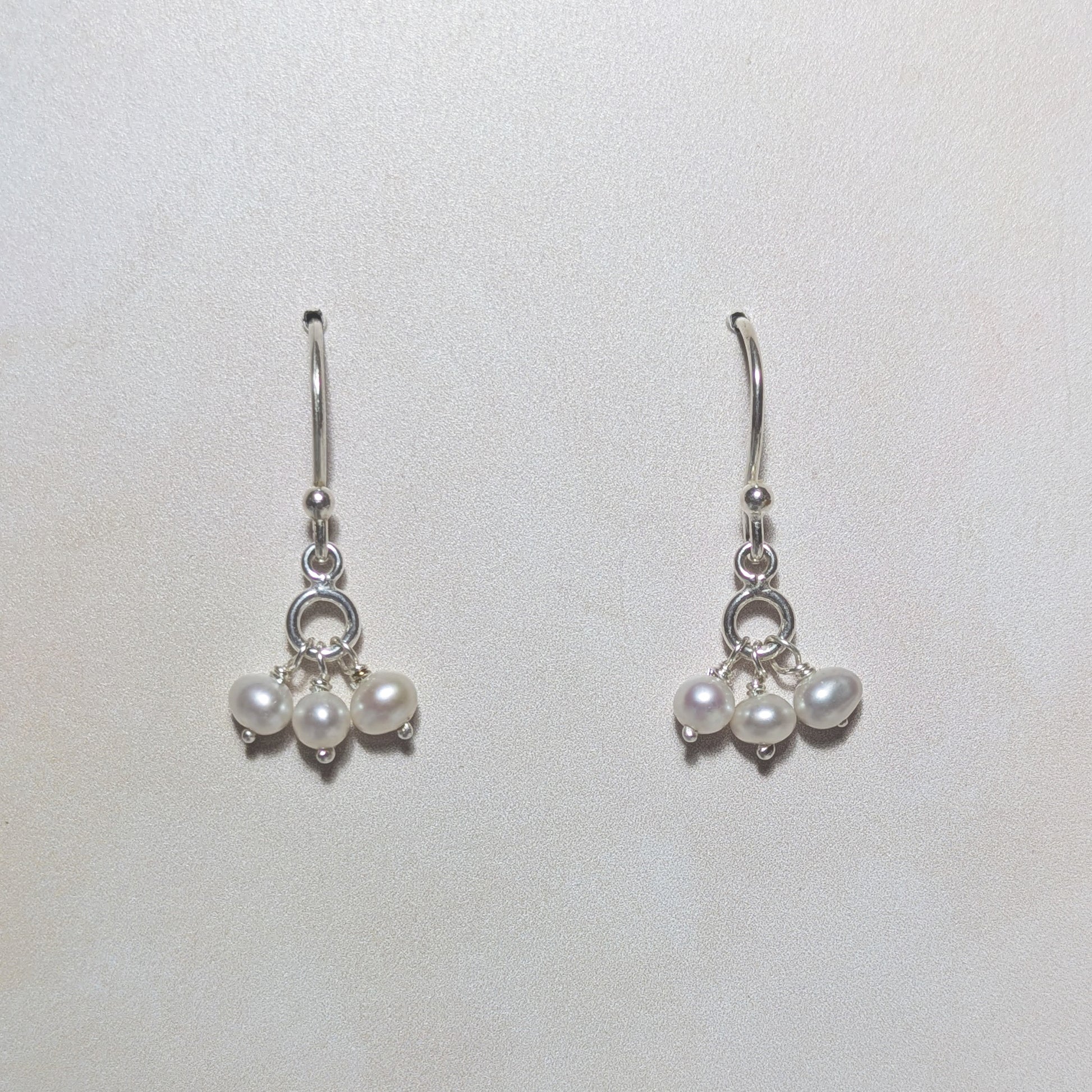 silver dangly drop earrings with freshwater pearl beads on a white background.