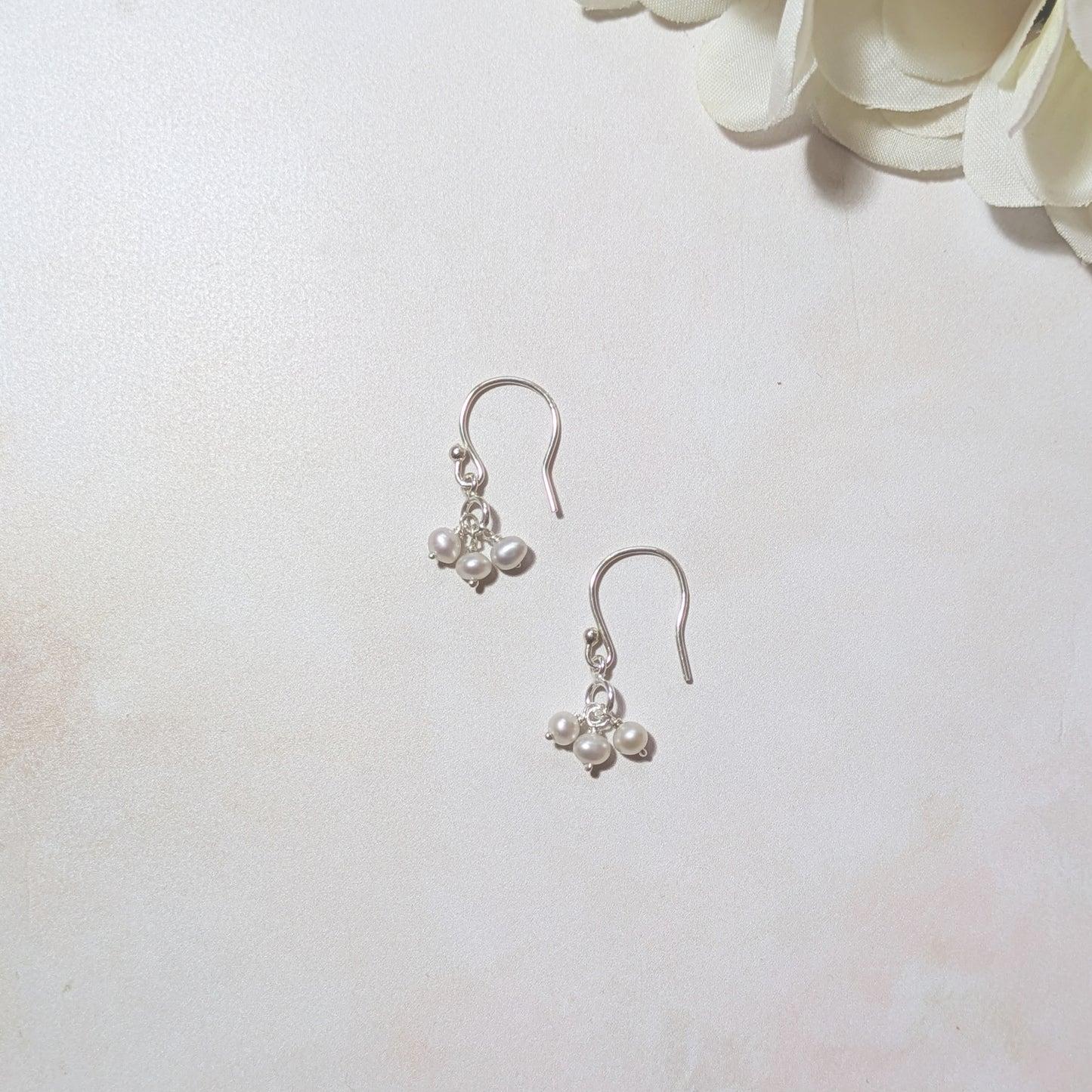 silver hookwire drop earrings with freshwater pearl beads on a neutral background.