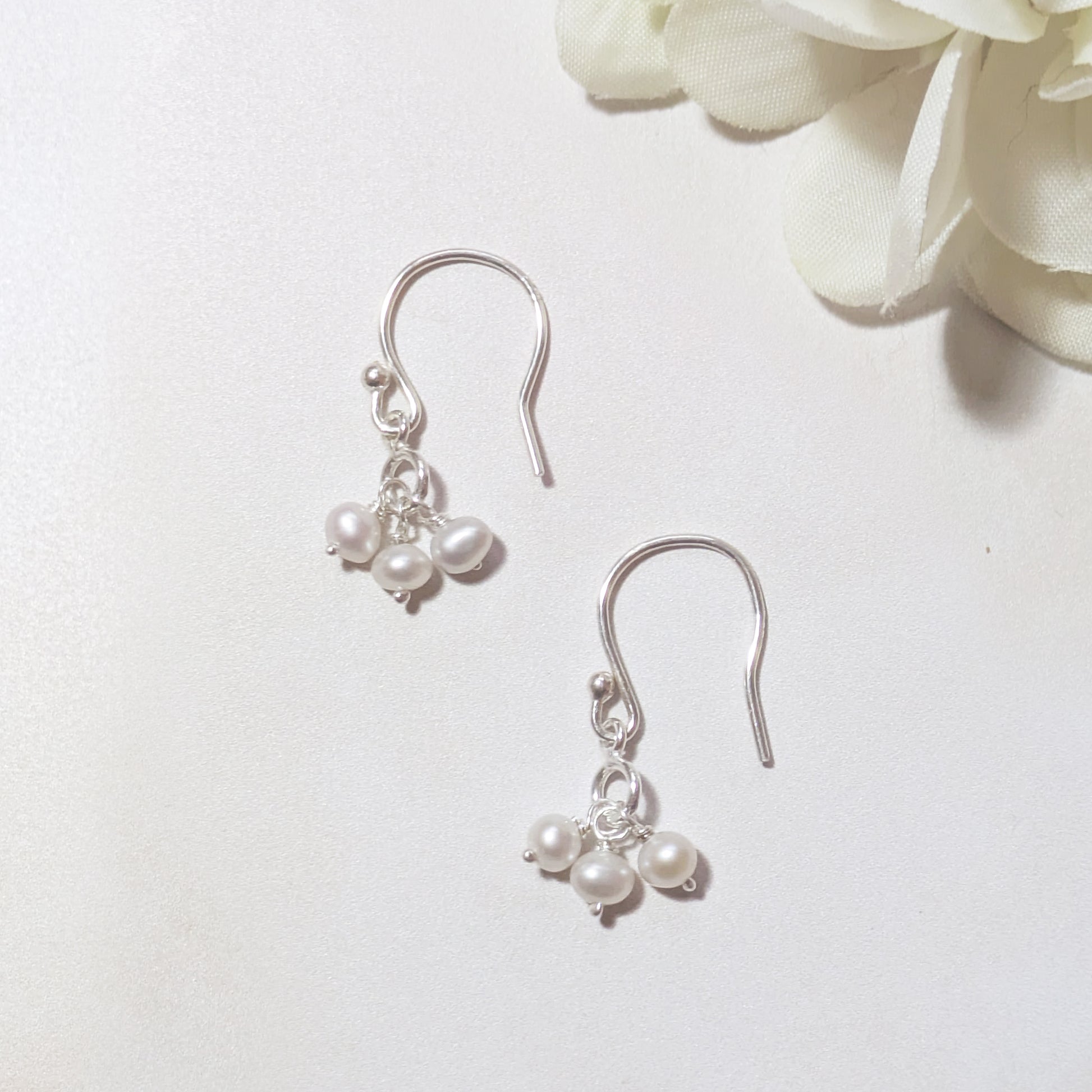 silver drop earrings with pearl drops on a white background.
