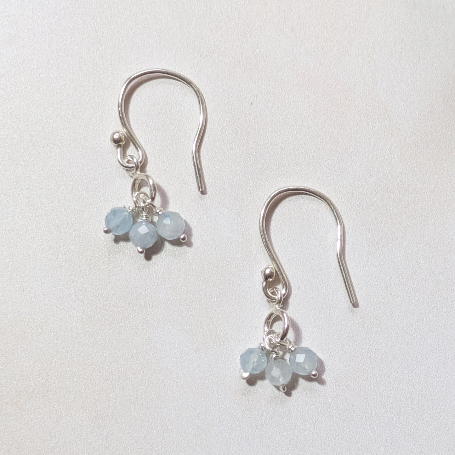 Pair of silver drop earrings with pale blue Aquamarine beads on a white background.