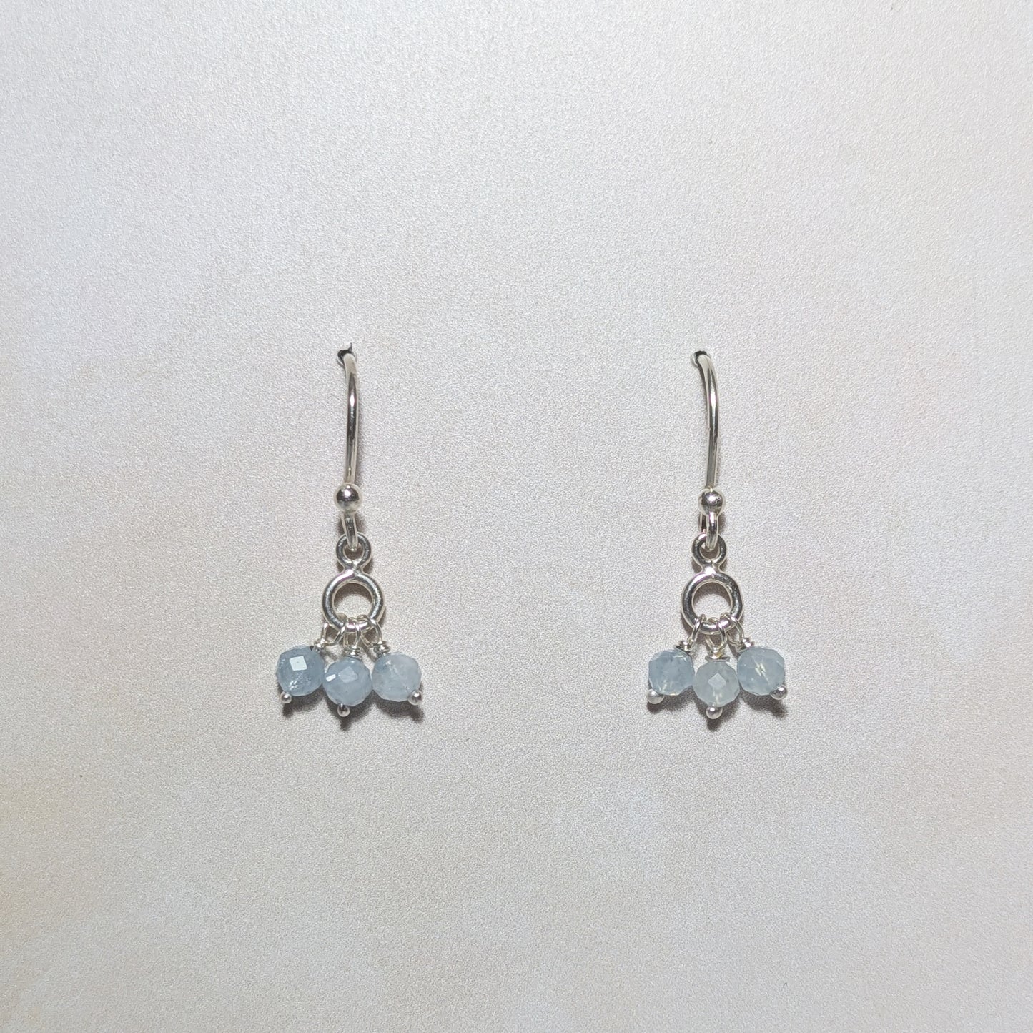 Silver earrings with light blue Aquamarine gemstone beads on a white background.