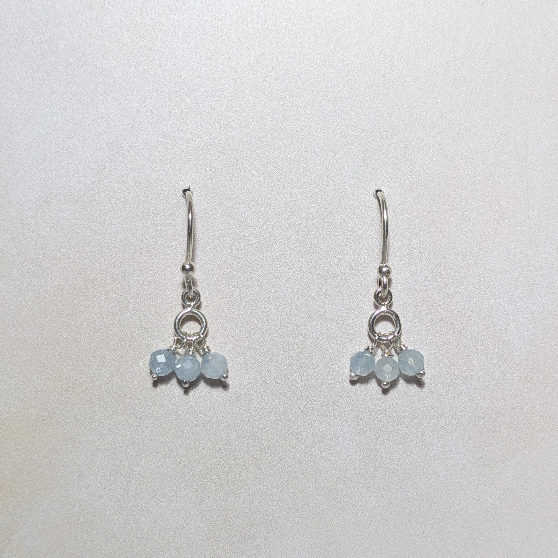 Silver earrings with light blue Aquamarine gemstone beads on a white background.
