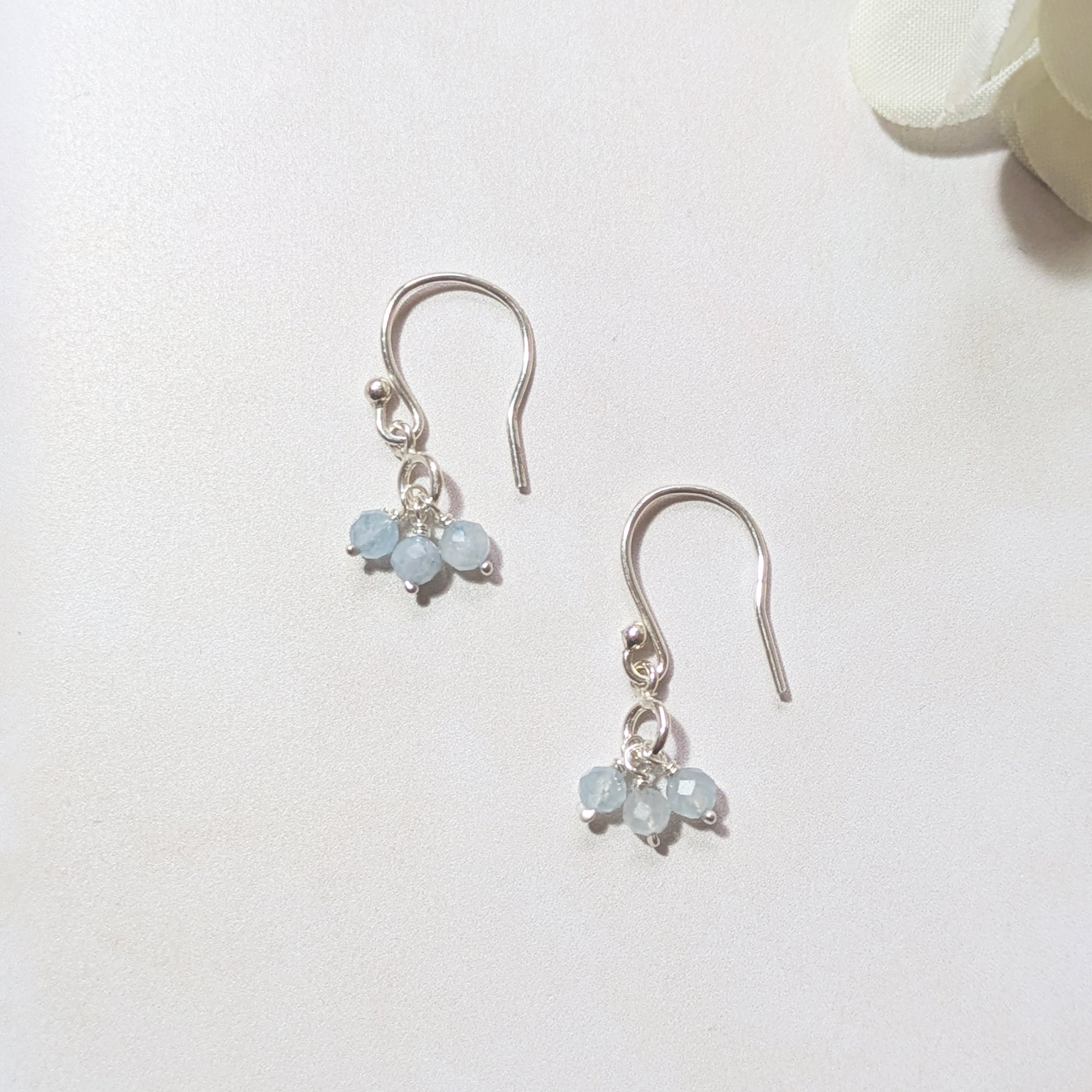 Silver drop earrings with pale blue Aquamarine gemstone drops on a white background.