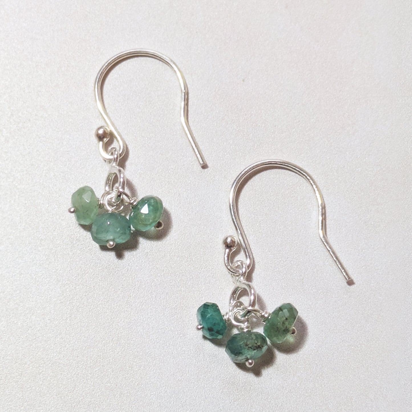 silver earrings with Emerald gemstone bead charms on a white background.