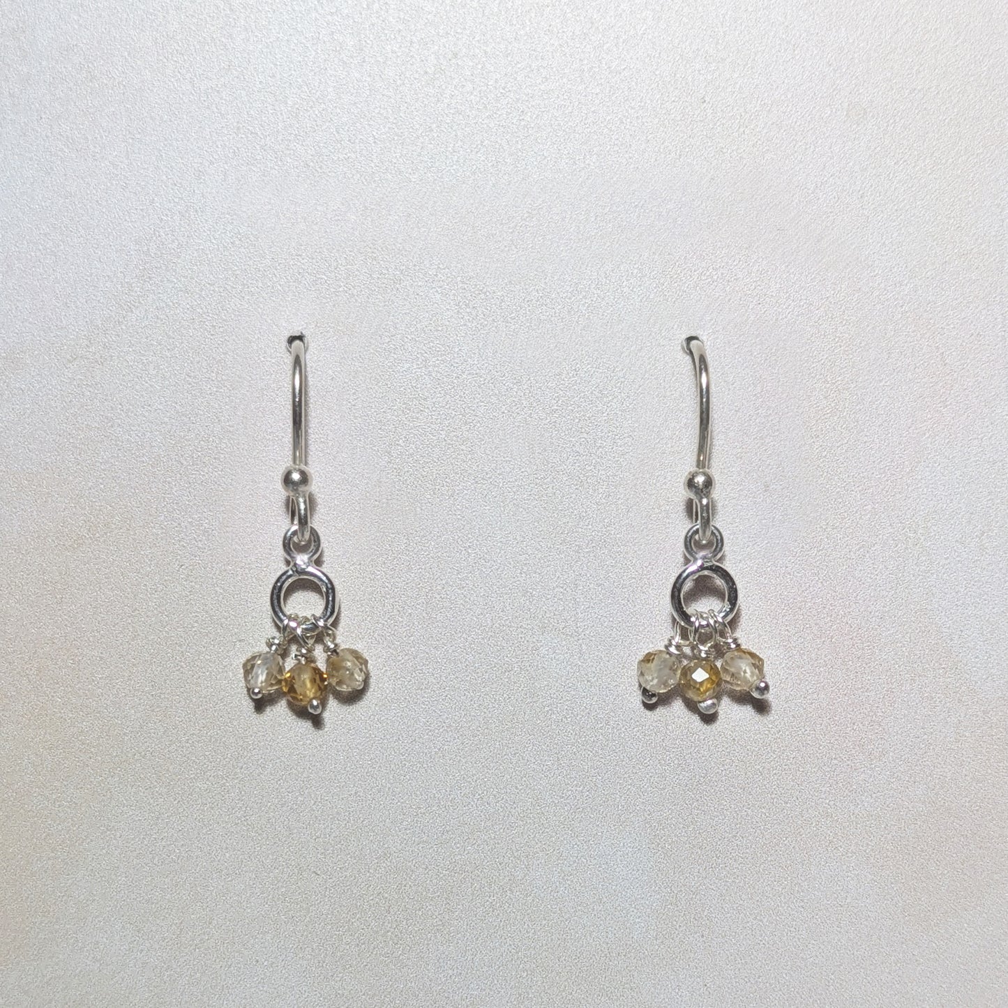 Pair of silver earrings with Citrine gemstone drops on a white background .