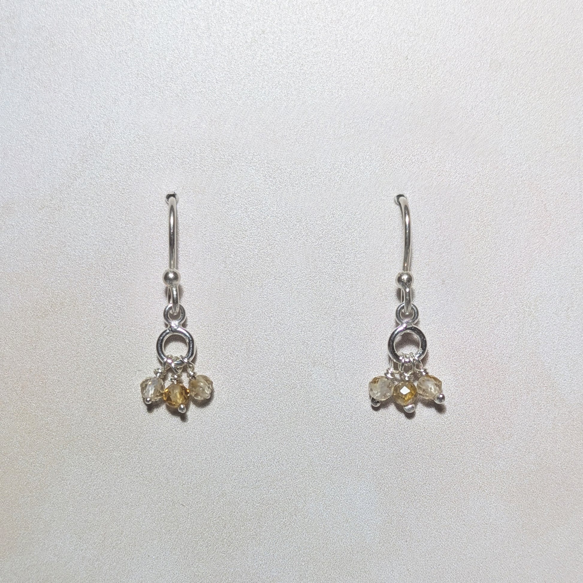 Pair of silver earrings with Citrine gemstone drops on a white background .