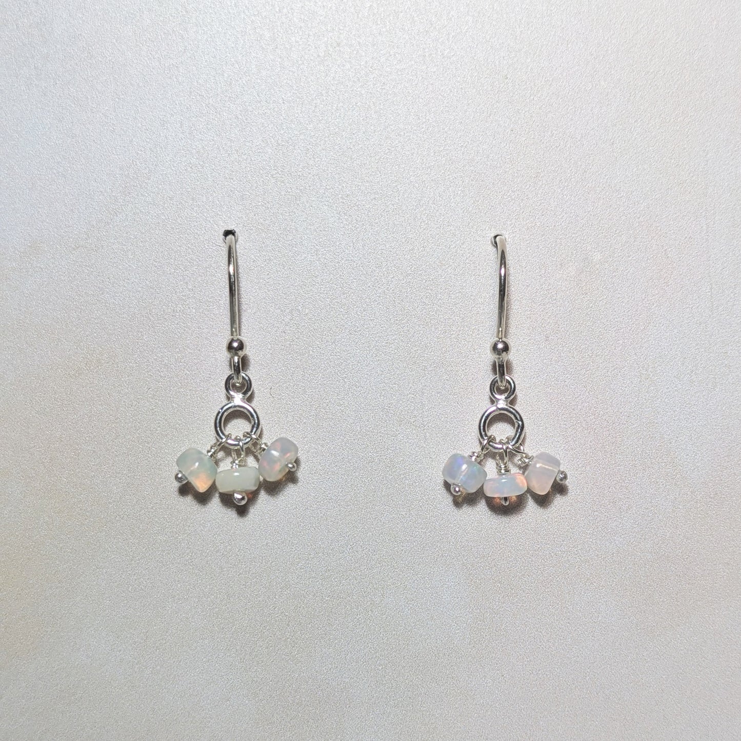 silver drop earrings with Opal gemstone bead charms on a pale neutral background.