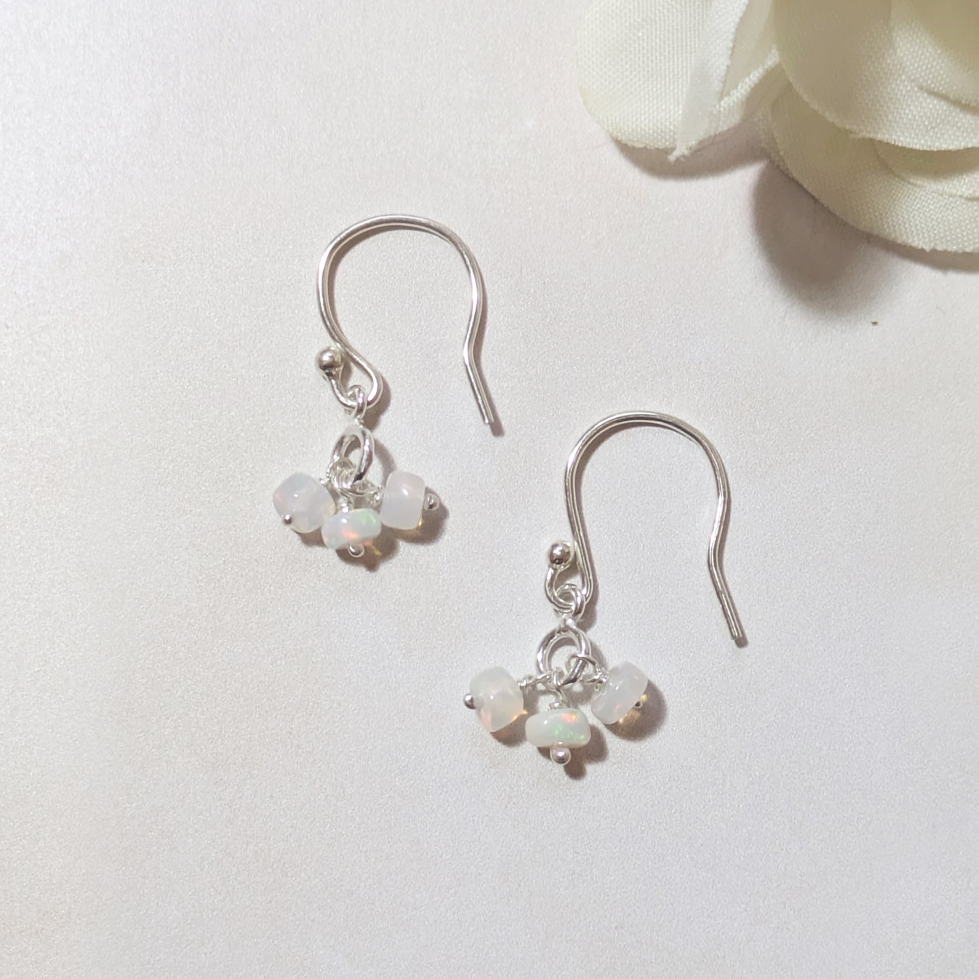 Silver earrings with small Opal beads on a white background.