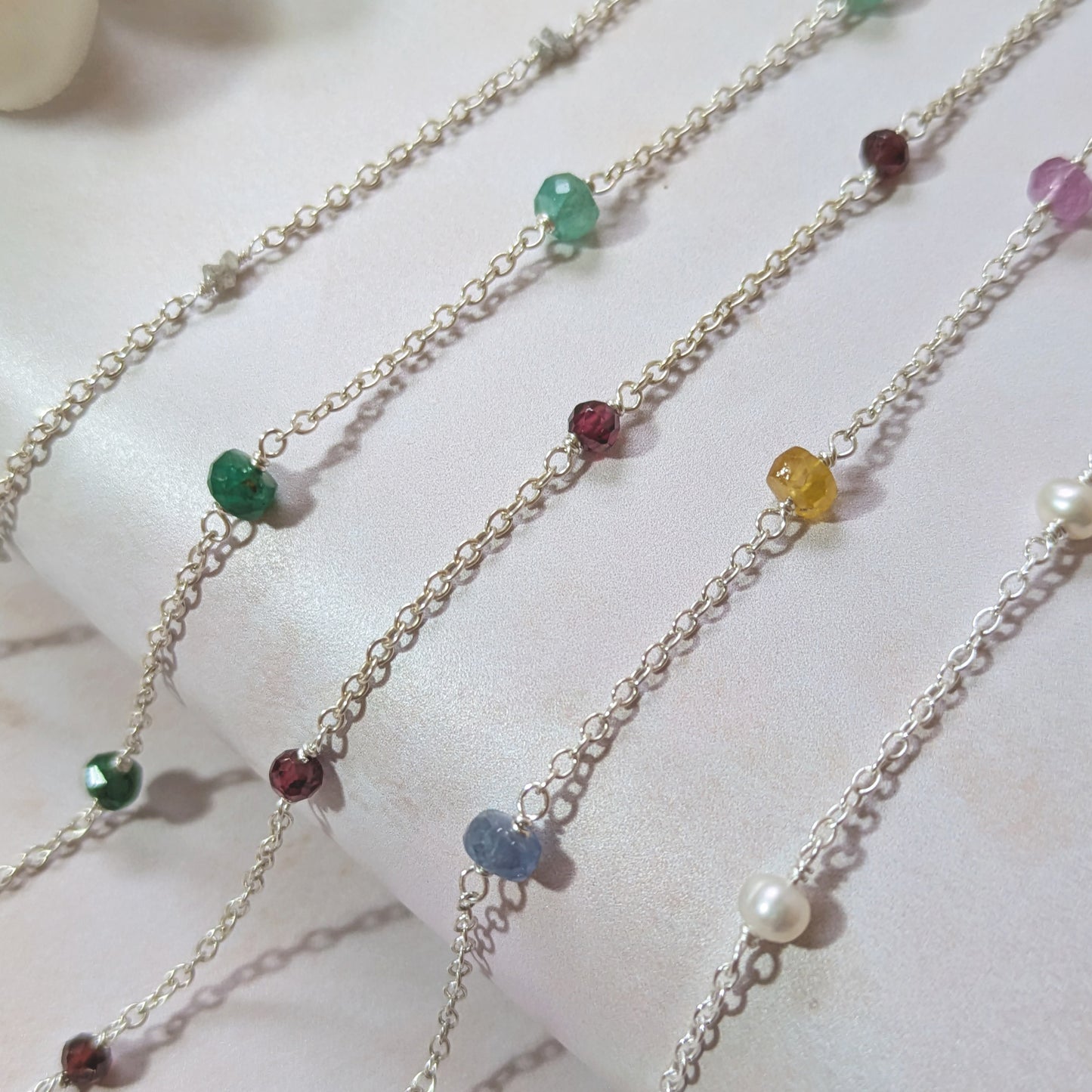 Multiple birthstone bracelets with colourful gemstone beads on a white background.