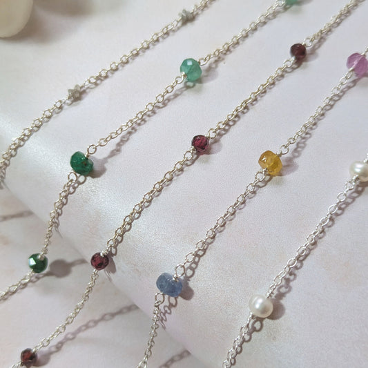 Multiple birthstone bracelets with colourful gemstone beads on a white background.