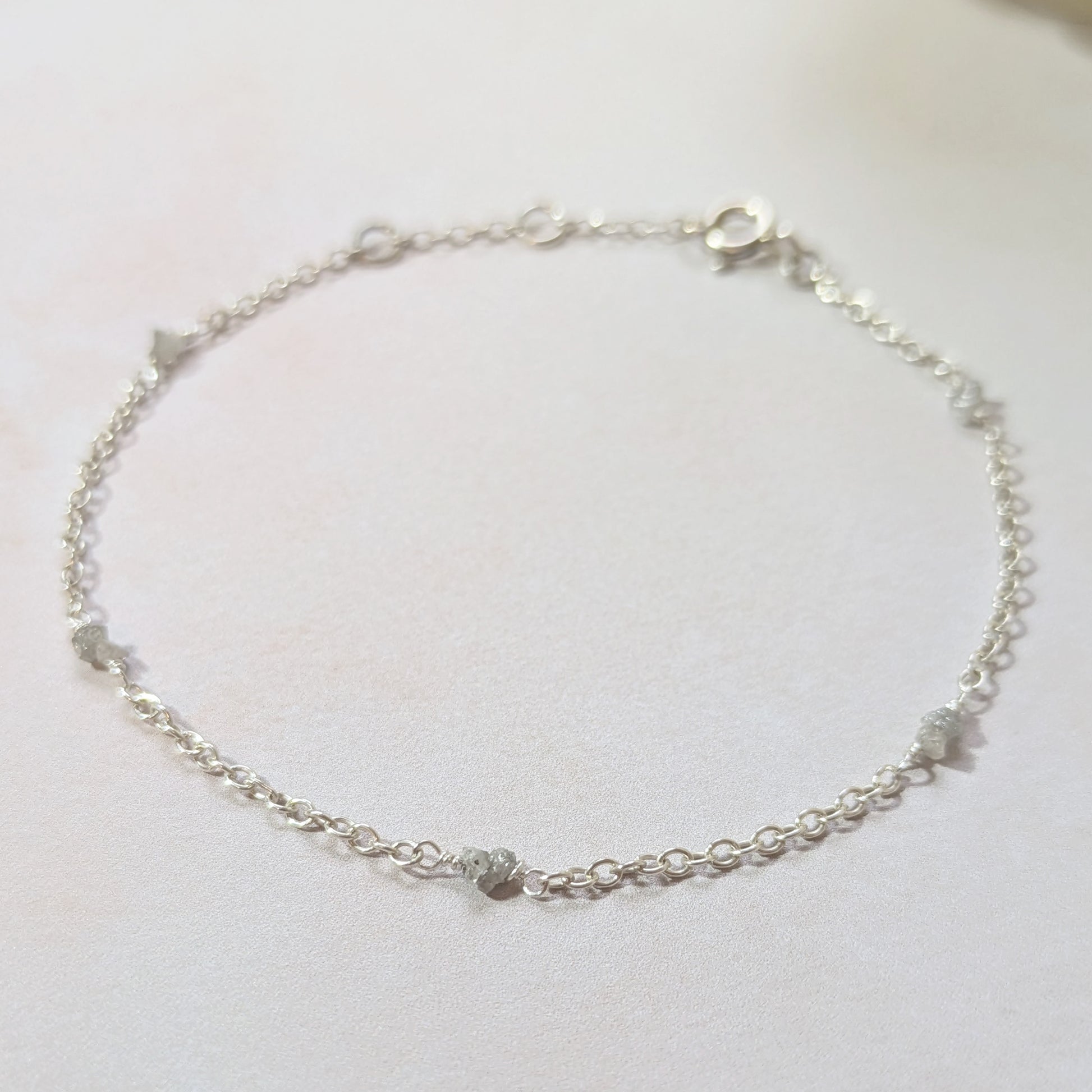 Silver stationed bracelet with raw Diamond nuggets on a white background.