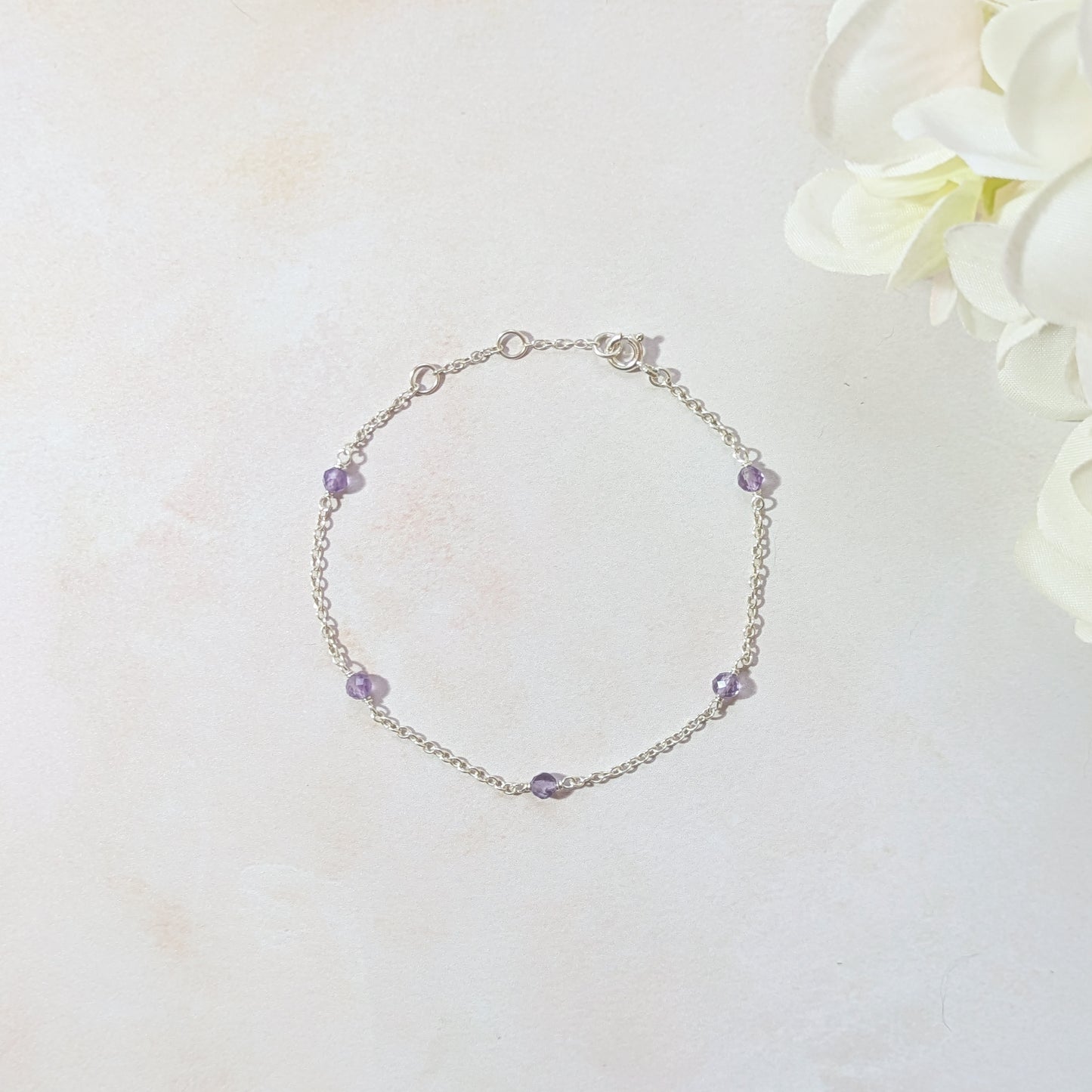 Silver stationed bracelet with Amethyst gemstone beads on a light background.