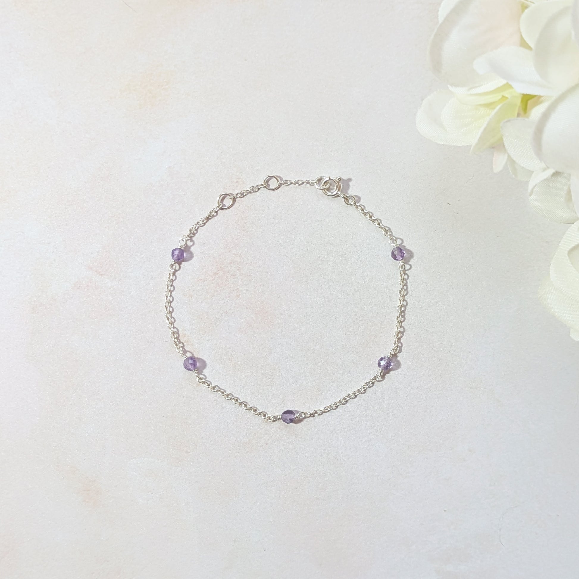 Silver stationed bracelet with Amethyst gemstone beads on a light background.
