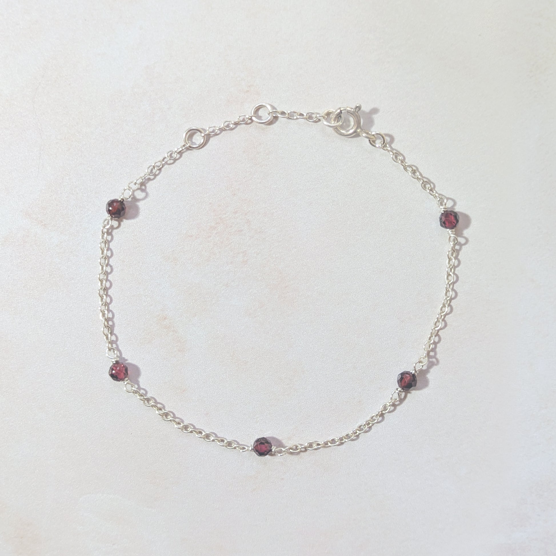 Silver bracelet with Garnet beads on a white background.