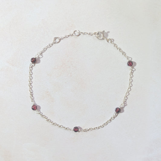 Silver bracelet with Garnet beads on a white background.