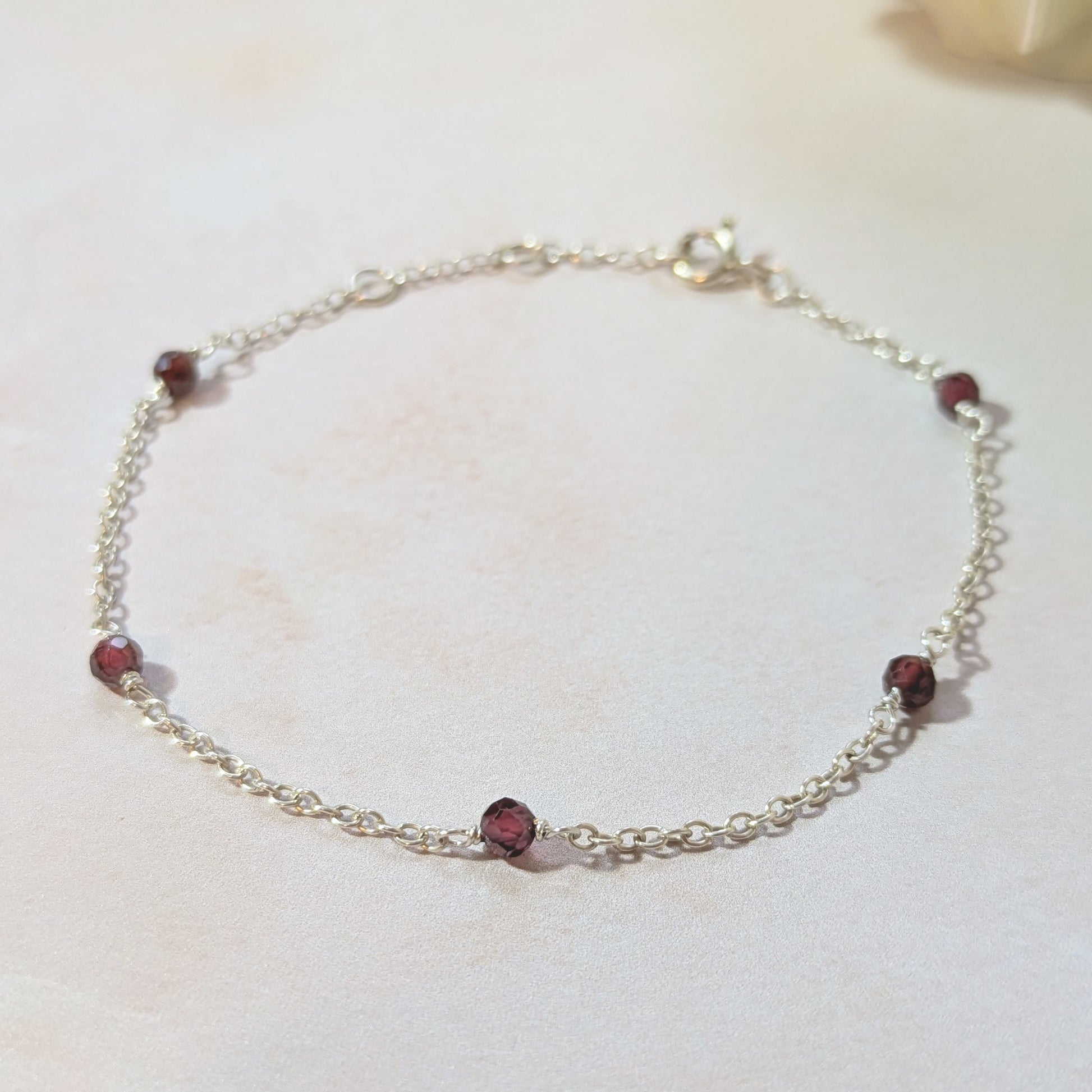 Silver stationed bracelet with red Garnet gemstone beads on a white surface.