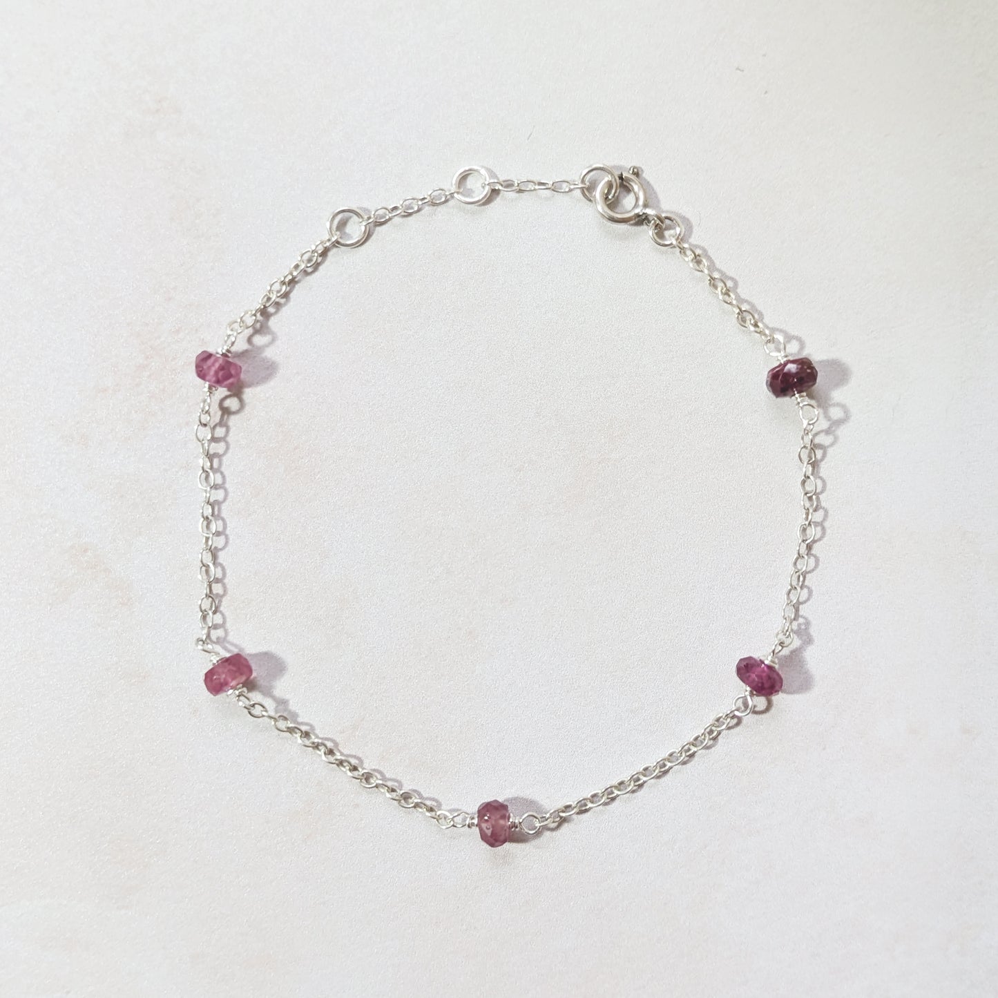 Silver chain bracelet with Rubies on a light background.